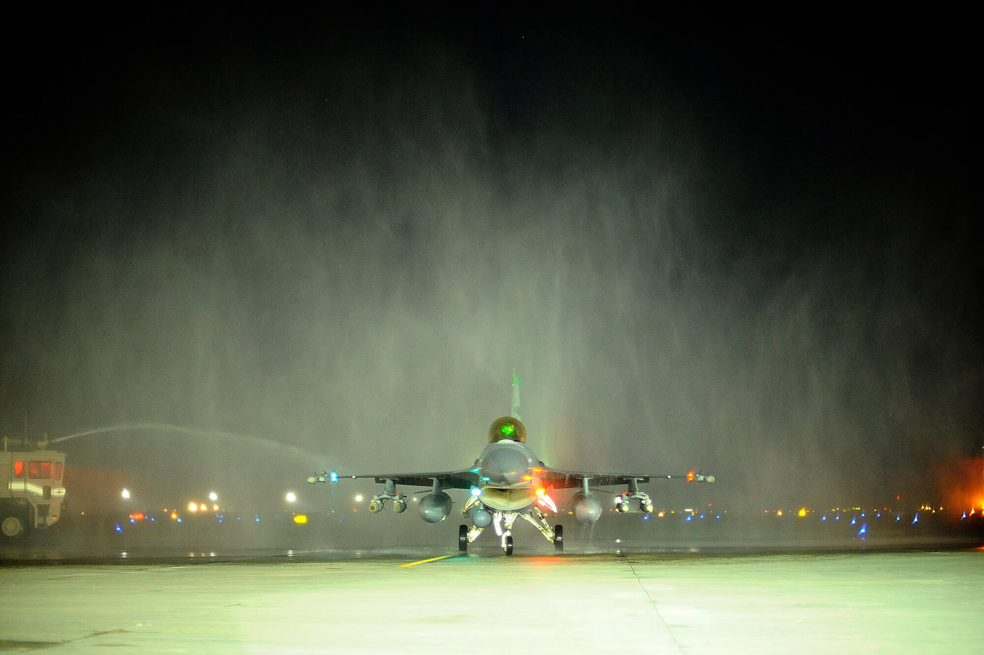 Col. David Romuald, 332nd Expeditionary Operations Group deputy Commander, taxis under the spray of two fire department crash trucks at Joint Base Balad, Iraq, after he completed his 3,000th flying hour in an F-16 Fighting Falcon Dec. 2. Cols. Michael Fantini and John Dolan also completed their 3,000th F-16 flying hour that evening. Approximately 150 F-16 pilots have surpassed this milestone. Fantini is the commander of the 332nd Expeditionary Operations Group and Dolan is the 332nd Air Expeditionary Wing vice commander. (U.S. Air Force photo/Airman 1st Class Jason Epley) (Released)