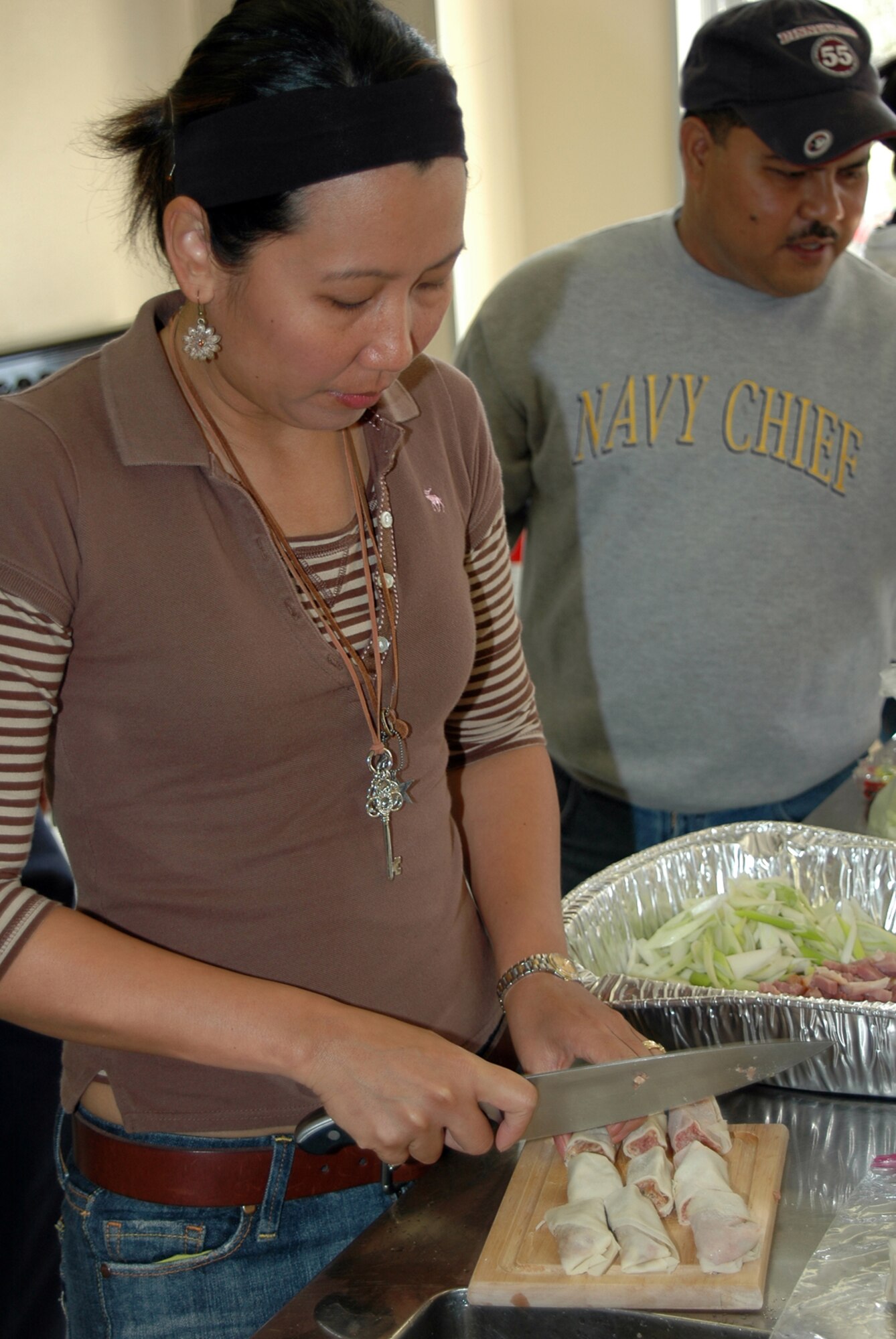 MISAWA AIR BASE, Japan -- Family member Gina Cable cuts freshly-rolled lumpia while Chief Petty Officer John Reyes, Naval Air Facility Misawa, surveys the process, during a fund-raising luncheon benefiting the Naval Air Facility Misawa's Family Readiness Group Oct. 28, 2008. The FRG meets monthly and works to improve quality of life programs for the facility's Sailors and their families. The luncheon raised nearly $400. (U.S. Navy photo by Chief Petty Officer Brian Naranjo)
