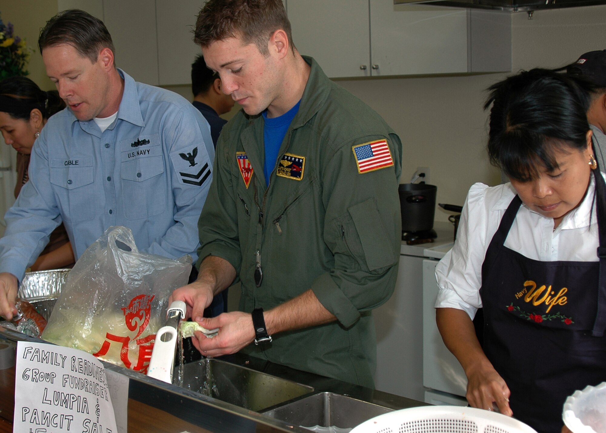 MISAWA AIR BASE, Japan -- Petty Officer 2nd Class Randall Cable, Naval Air Facility Misawa, Petty Officer 2nd Class Dustin Schmidt, Naval Air Facility Misawa, and family member Daisy Haugen prepare a gourmet Filipino meal of homemade lumpia, pancit and rice during a fund-raising luncheon benefiting the Naval Air Facility Misawa's Family Readiness Group Oct. 28, 2008. The FRG meets monthly and works to improve quality of life programs for the facility's Sailors and their families. The luncheon raised nearly $400. (U.S. Navy photo by Chief Petty Officer Brian Naranjo)