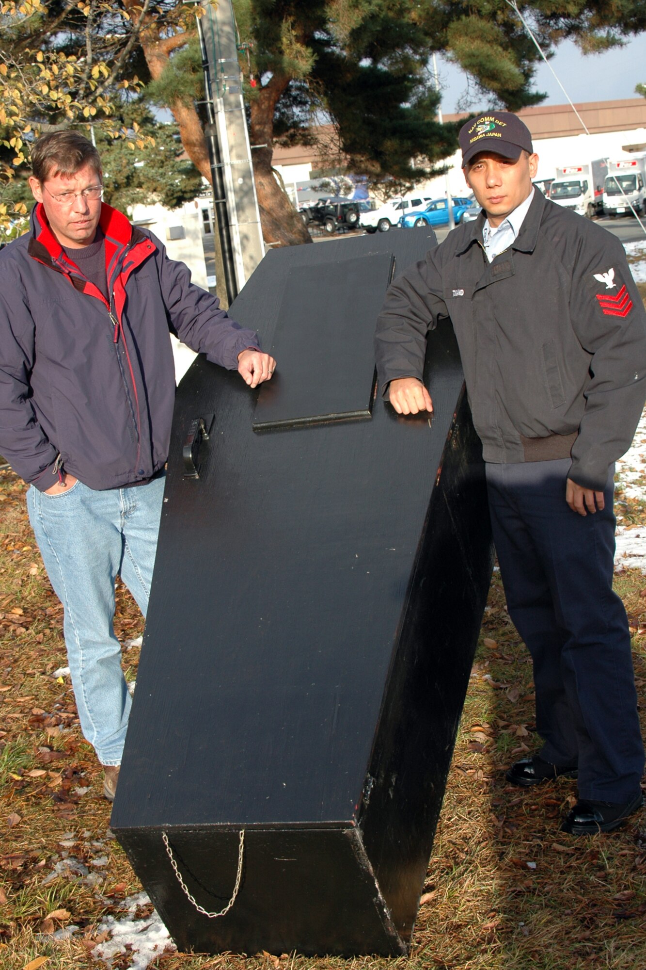 MISAWA AIR BASE, Japan -- Jeffrey Wilson, Naval Air Facility Misawa safety manager, and Petty Officer 1st Class Harry Turnland, Naval Air Facility Misawa, pose at a coffin that's part of a new holiday driving under the influence awareness display near the Misawa Air Base front gate, Nov. 20, 2008. The display is intended to serve as an added reminder of the consequences of driving after consuming alcohol. Mr. Wilson planned and designed the display, with the support of Misawa Navy and Air Force commanders. (U.S. Navy photo by Chief Petty Officer Brian Naranjo)