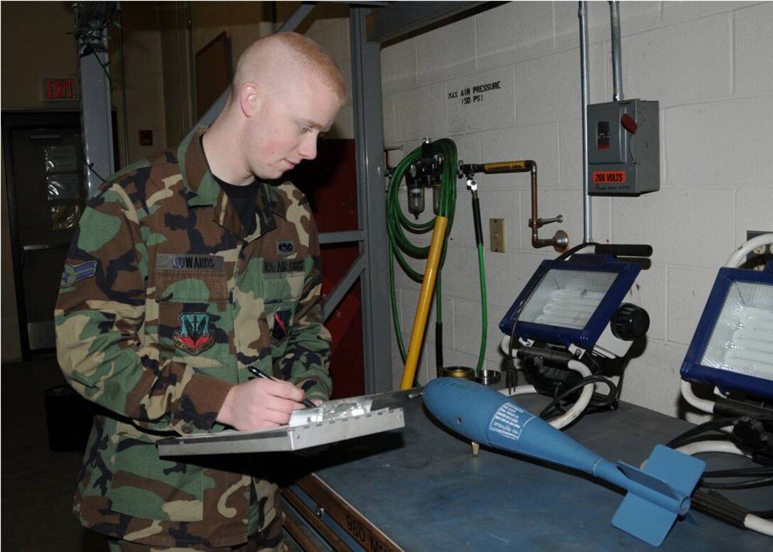 Airman Edwards inspects the serial number off a practice bomb.  Photo by Master Sgt. Mark Fortin