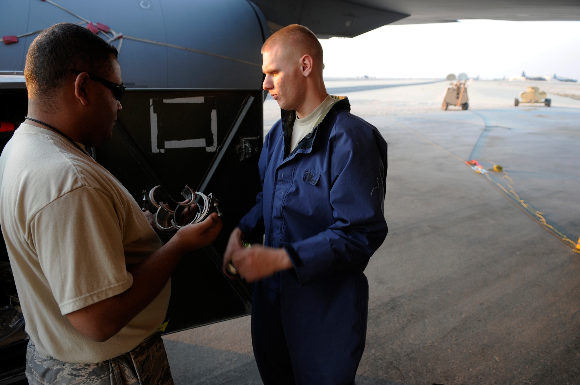 Staff Sgt. Eric Holmes and Airman 1st Class Thomas Browne, fuels system technicians assigned to the 379th Expeditionary Maintenance Squadron, discuss which clamps are needed for the aircraft refuel line on a KC-135 Stratotanker, Dec. 5, at an undisclosed air base in Southwest Asia.  The repair team replaced the center wing tank in response to a fuel leak problem.  The KC-135 provides the core aerial refueling capability for the United States Air Force and also provides aerial refueling support to Navy, Marine Corps and allied nation aircraft in the Central Command area of responsibility.  Sergeant Holmes, a native of Brandon, Fla., is deployed from McConnell Air Force Base, Kan.  Airman Browne hails from Manchester, N.H., and is deployed from Grand Forks AFB, N.D.  Both are deployed in support of Operations Iraqi and Enduring Freedom and Joint Task Force-Horn of Africa.  (U.S. Air Force photo by Tech. Sgt. Michael Boquette/Released)