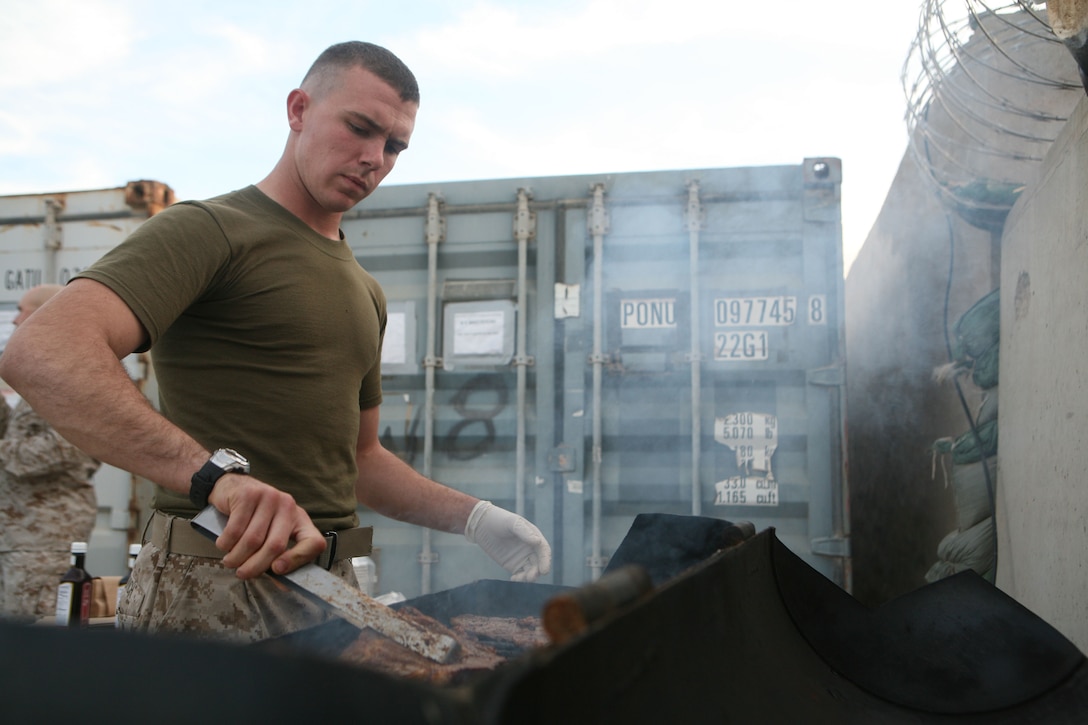 Lance Cpl. Nathaniel Z. Udovich, a 21-year-old mail clerk from Trenton, Mo., prepares chicken and steak at Camp Baharia, Iraq, Dec. 7. Marines with Headquarters and Service Company, 1st Battalion, 4th Marines, held a barbecue to take their minds off of daily operations.