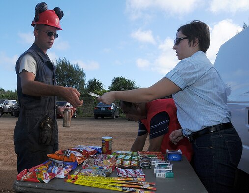 ANDERSEN AIR FORCE BASE, Guam - Laurie Parker gives Staff Sgt. Dereck Ross, 554th REDHORSE Squadron, his change after he makes his purchase from the  "mini shopette"  at Northwest Field on Dec. 5 here.   Army Air Force Exchange Service employees like Laurie, drive out to NWF on their days off to provide Airmen snacks and beverages before reporting to their work sites.  (U.S. Air Force photo by Staff Sgt. Jamie Lessard)  