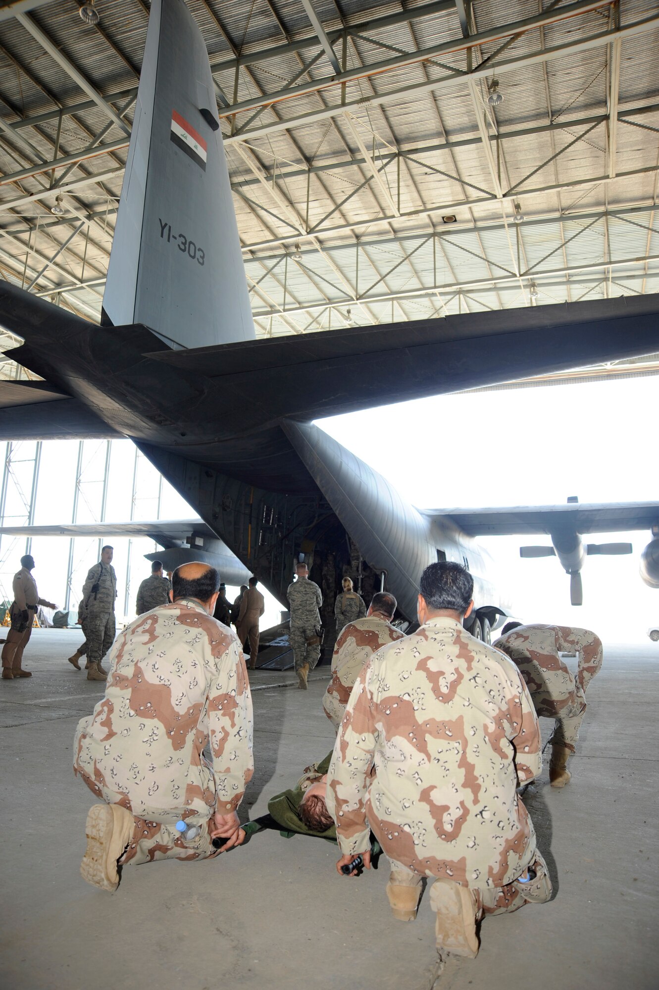 Iraqi air force medics prepare to load a mock patient into a C-130 Hercules aircraft for a demonstration for Iraqi senior leadership during their graduation ceremony at New Al-Muthana Air Base, Iraq, Dec. 4. The Iraqi airmen completed a 12-day aeromedical evacuation basics course that covered reconfiguring a cargo aircraft into a medical patient aircraft, creating a load plan of patients and coordinating with ground support to load patients. (U.S. Air Force photo/Staff Sgt. Paul Villanueva II)