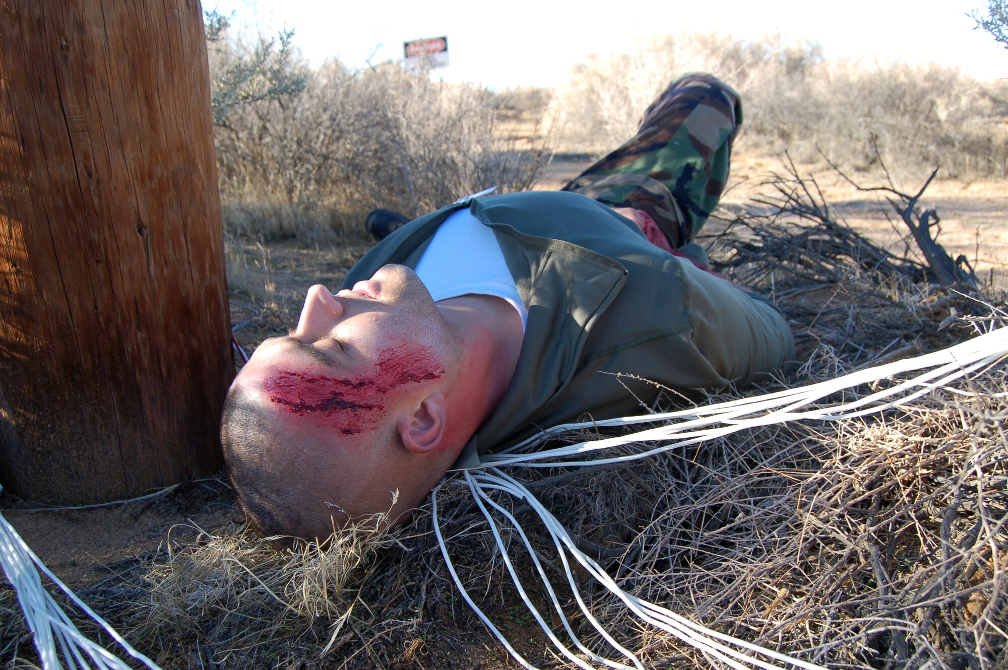 Staff Sgt. Charles Cisney, 31st Test and Evaluation Squadron, lies on Edwards desert as he plays a pilot of a F-16 Fighting Falcon that "crashed" during an Emergency Management Exercise Dec. 3. The exercise tested the base's disaster response capability. (Air Force photo by Senior Airman Julius Delos Reyes)