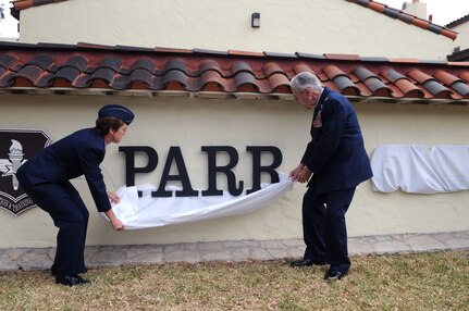 Col. Jacqueline Van Ovost, 12th Flying Training Wing commander, and Korean War ace, retired Col. Ralph Parr, unveil the new sign in front of the newly-renamed "Parr Club" during a ceremony Dec. 5. (U.S. Air Force photo by Rich McFadden)