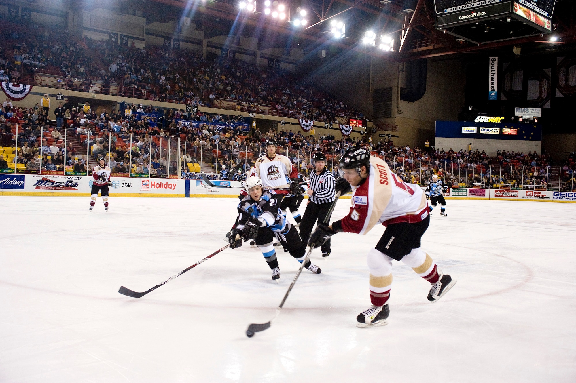 ANCHORAGE, Alaska -- Bakersfield Condor's Tyler Scott skates with puck while Alaska Aces' Luke Erickson chases after him at Aces' military appreciation game Dec. 6. The Aces won 6-0 to the Condors. (U.S. Air Force photo/Senior Airman Jonathan Steffen)