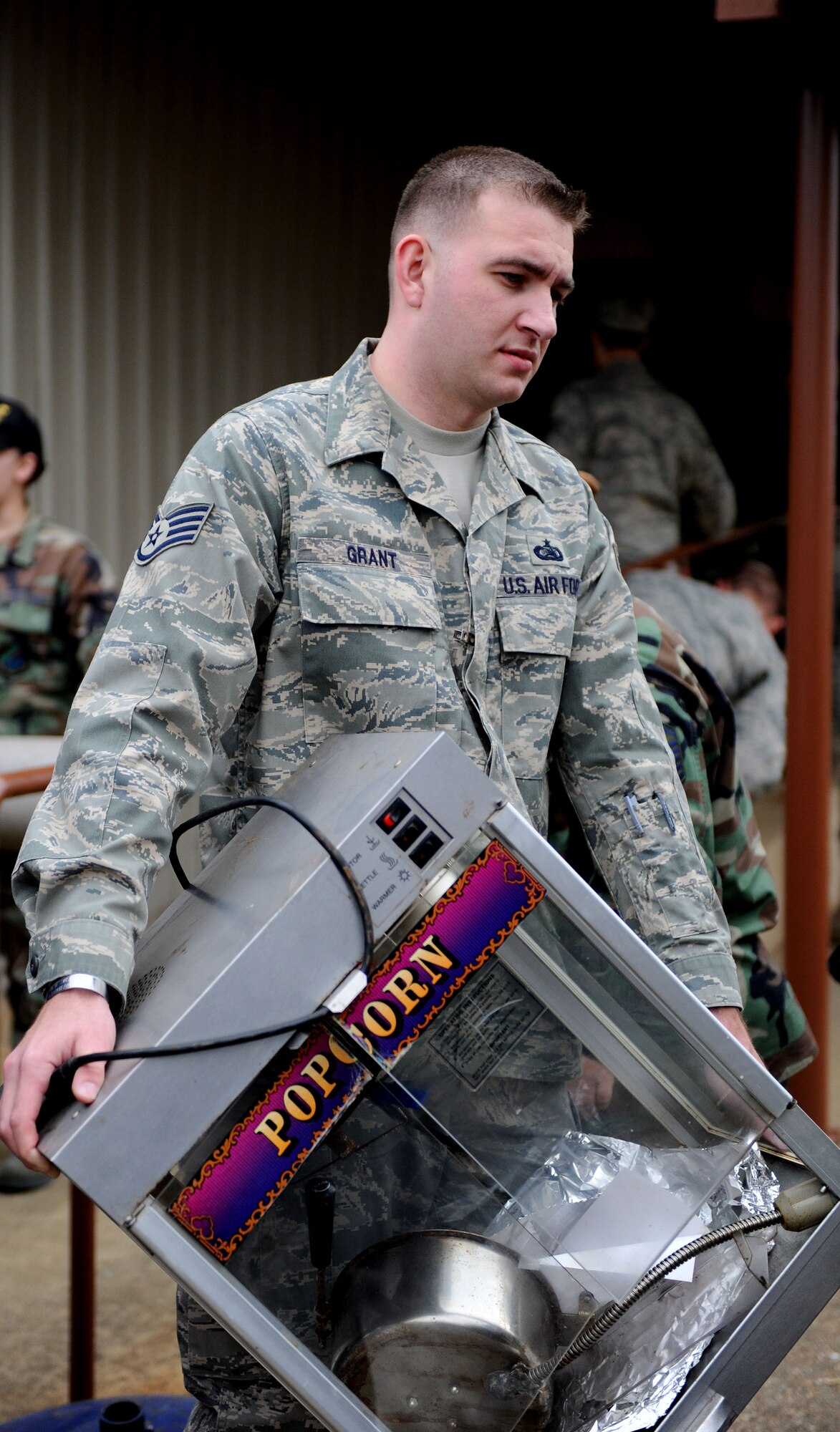 LANGLEY AIR FORCE BASE, Va. -- Staff Sgt. Robert Grant from the 83rd Network Operations Squadron carries a popcorn machine from the Airmen's Attic to a loading truck Dec. 5. Approximately 60 Airmen volunteered on the squadron's Wingman Day to move items to a storage facility allowing the Airmen's Attic to expand. (U.S. Air Force photo/Airman Rebecca Montez)