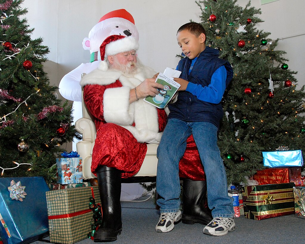 Coulter Dawson, 8, a 2nd grader at Scotland Park Elementary School, sits on Santa's lap and reads his letter to Santa during the Give a Child a Child a Christmas event held Friday afternoon. (U.S. Air Force photo/Harry Tonemah)