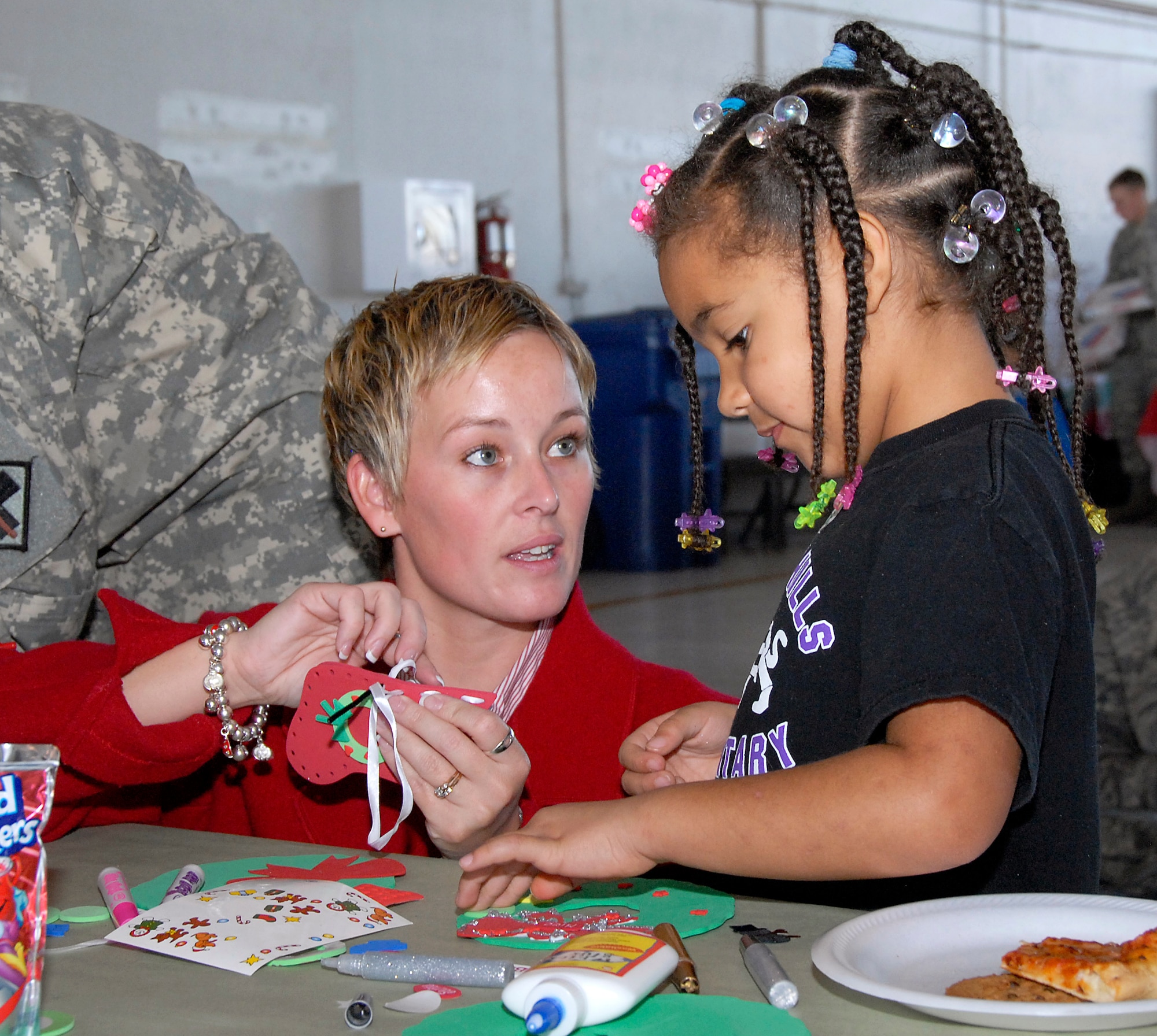 Amy Preskitt who works Civil Service at Sheppard helps Chloe Free, 5, who is in kindergarten at Southern Hills Elementary, make a stocking and wreath decoration for her Christmas tree at the Give a Child a Christmas held in Hangar 1090 Dec. 5. (U.S. Air Force photo/Harry Tonemah)