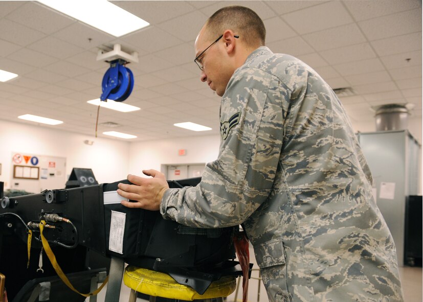 Airman 1st Class Raymond Hernandez, 4th Component Maintenance Squadron Egress Shop, checks for any anomalies in the parachute on the top of the ejection chair Dec.4, 2008, on Seymour Johnson Air Force Base, N.C. The egress shop mission is to ensure the safety of the aircrews’ life. (U.S. Air Force photo by Airman 1st Class Whitney S. Stanfield)