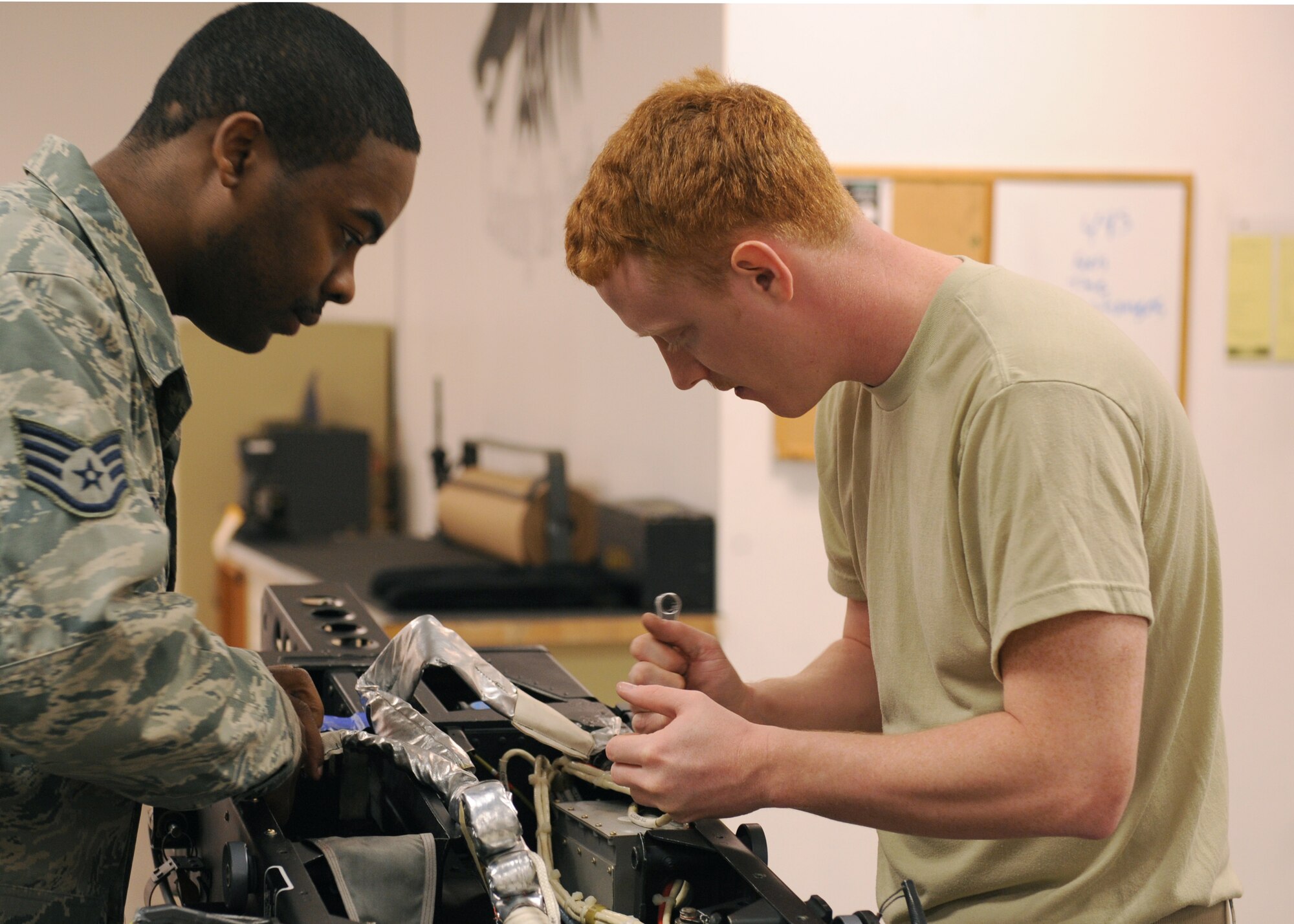Staff Sgt. Julius Petaway and Senior Airman Jonathan Bertini, both from the 4th Operations Support Squadron, place the drogue parachute in the back of the ejection seat Dec. 4, 2008, on Seymour Johnson Air Force Base, N.C. A drogue parachute comes out the back of the ejection seat to keep the chair upright so it glides through the air more smoothly. (U.S. Air Force photo by Airman 1st Class Whitney S. Stanfield) 
