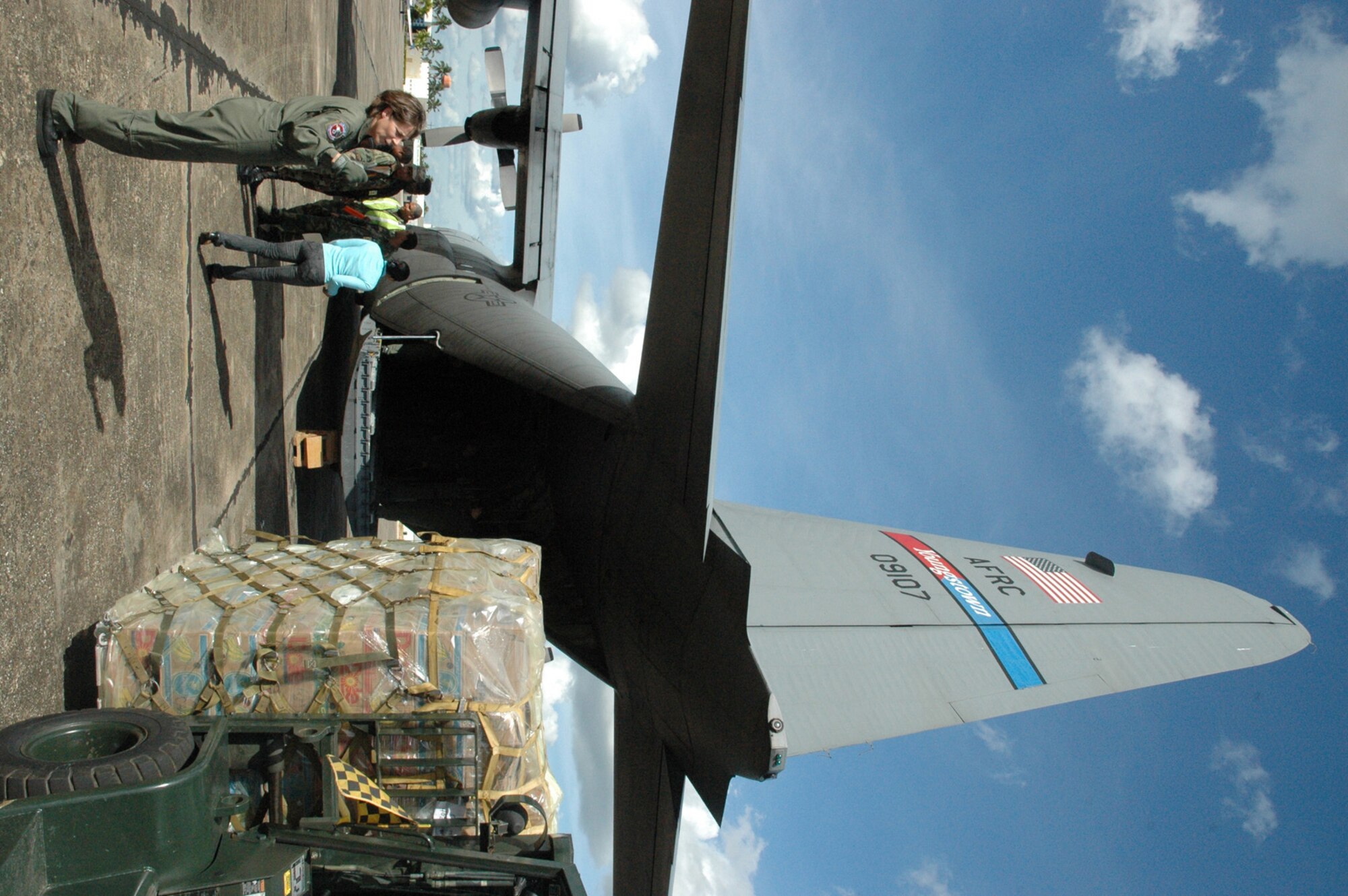SANTO DOMINGO, Dominican Republic -- Air Force Reservist Master Sgt. Christina Feliciano, a loadmaster with the 773rd Airlift Squadron, spots a local Domincan as he removes a pallet of donated clothing. Notre Dame Universitystudents and alumni along with many regional Rotarians have made it possible for struggling people of the Dominican Republic to receive much needed clothing after the devastation of Hurricane Olga in 2007. The Air Force Reserve's 910th Airlift Wing in Youngstown, Oh. and 911th Airlift Wing in Pittsburgh, PA. partnered to airlift approximately 60,000 pounds of donated new and used clothing aboard two C-130 Hercules aircraft.  This Air Force Reserve mission was made possible because of the Denton humanitarian program.  For more information about the Denton Program, visit: www.usaid.gov  U.S. Air Force photo by Capt. Brent J. Davis
