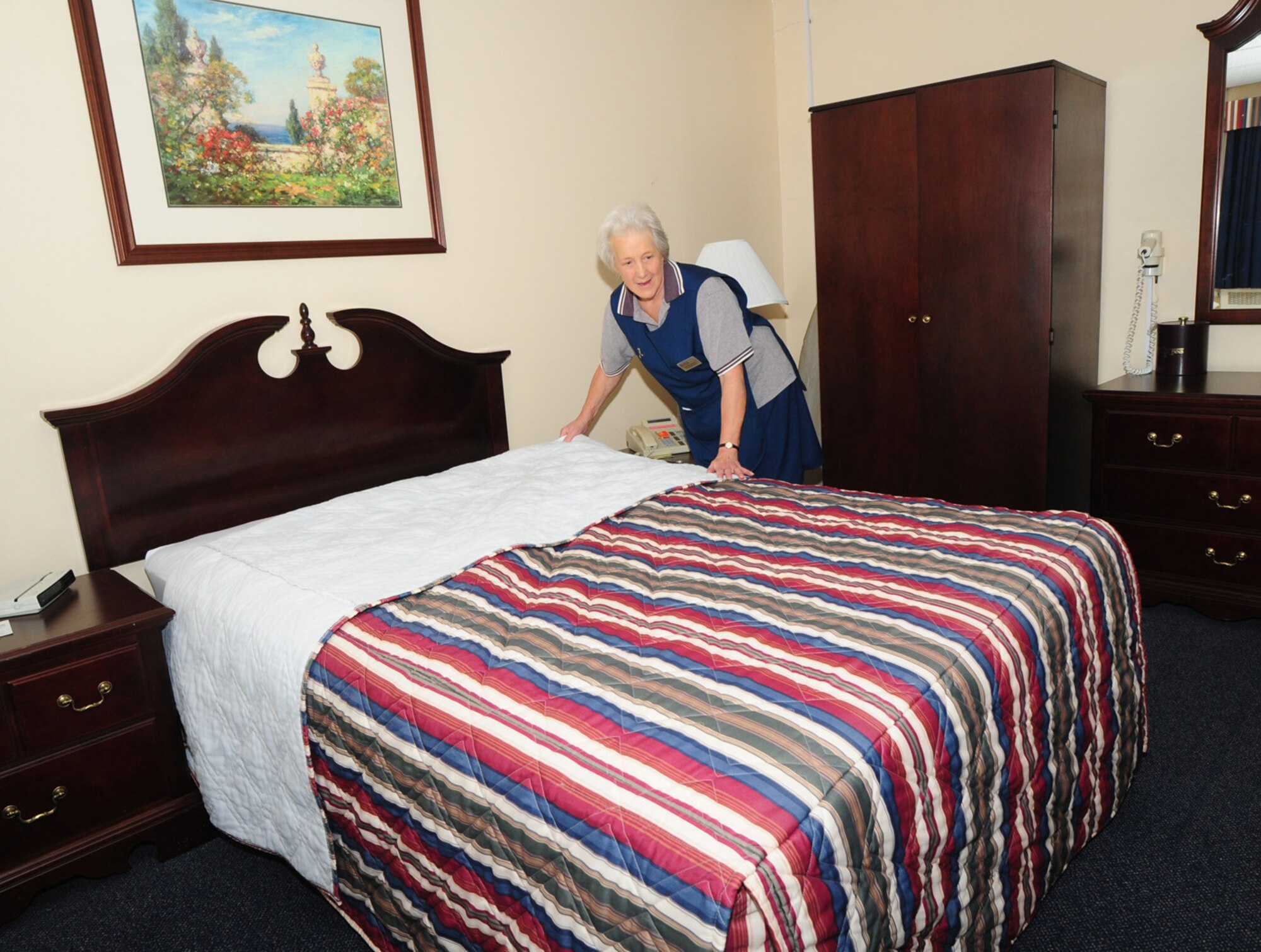 Heather Damsell, 100th Force Support Squadron Gateway Inn housekeeper, puts fresh sheets on the bed in one of the lodging rooms Nov. 21. Mrs. Damsell has worked at the Gateway Inn for 42 years, and is responsible for ensuring the rooms are kept spotlessly clean and bedding is changed daily. There are TLFs for families, pet-friendly TLFs and business suites for distinguished visitors – chief master sergeants, colonels and generals. (U.S. Air Force photo by Karen Abeyasekere)