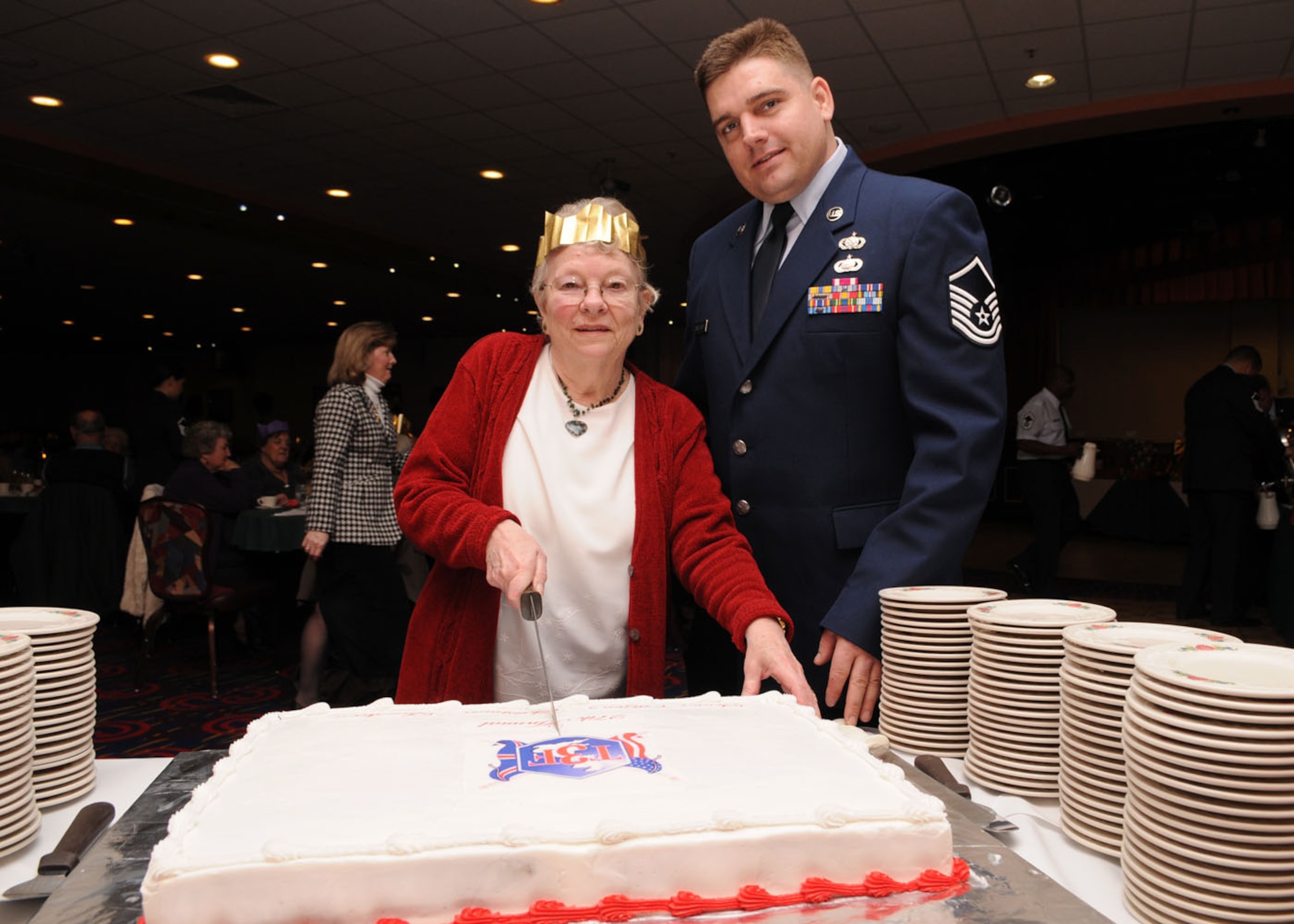 Master Sgt. David Caruthers from the 100th Force Support Squadron, assist  Pam Rich, from Mildenhall, with cutting the cake during the 27th annual Senior Citizens Luncheon Dec. 3, 2008, in RAF Mildenhall, England. (U.S. Air Force photo by Staff Sgt. Jerry Fleshman)