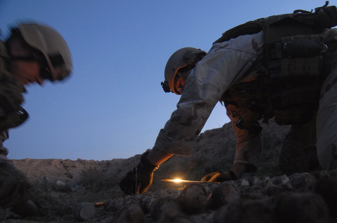 U.S. Navy Petty Officer 1st Class Ben Jones, left, and Aaron Ritter uncover buried projectile fuses in Tikrit, Iraq, Dec. 5, 2008.
