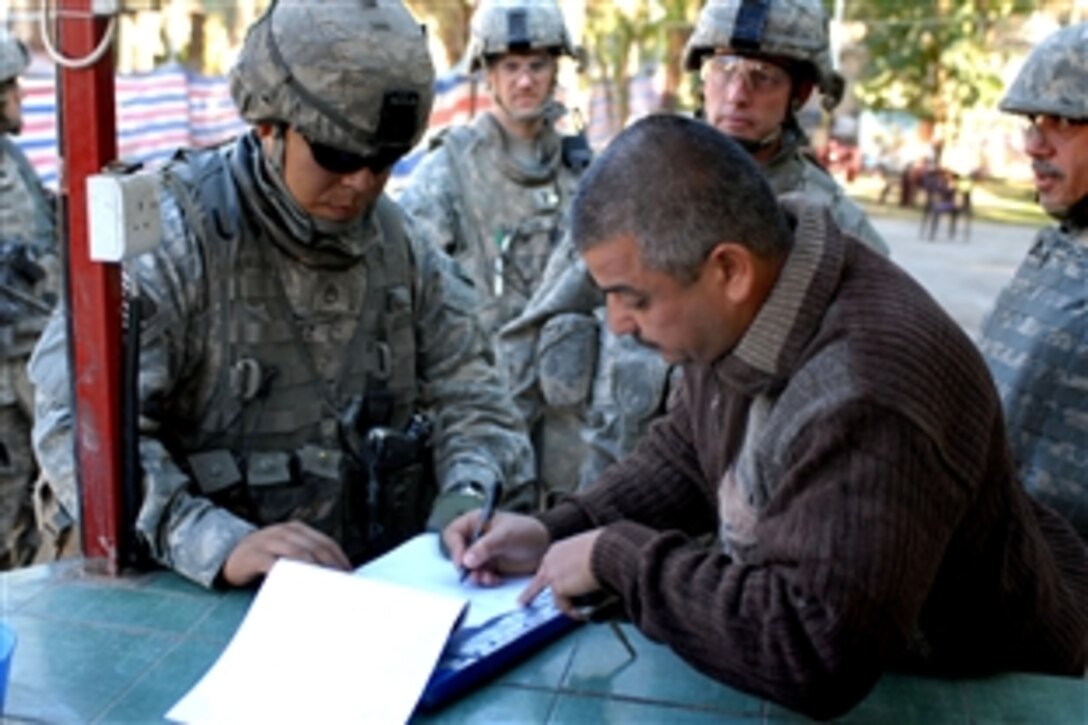 U.S. Staff Sgt. Reggie Martinez, left, helps an Iraqi shop owner complete paperwork for a micro grant to help his business in the Adhamiyah District of Baghdad, Iraq, Dec. 5, 2008. Martinez serves as a team leader with the 4th Infantry Division's Command Security Detachment, 3rd Brigade Combat Team, Multinational Division Baghdad.