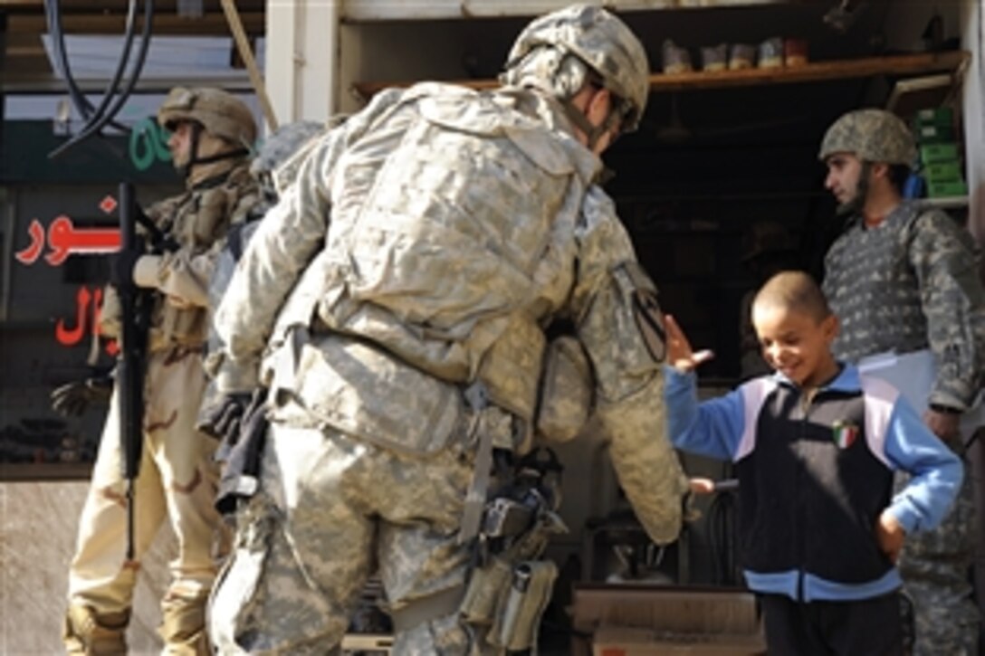 U.S. Army Capt. Alexander Rasmussen shows an Iraqi boy how to give a high five in the Al Karama neighborhood of Mosul, Iraq, Dec. 3, 2008. Rasmussen is assigned to the 8th Infantry Regiment's 1st Battalion.
