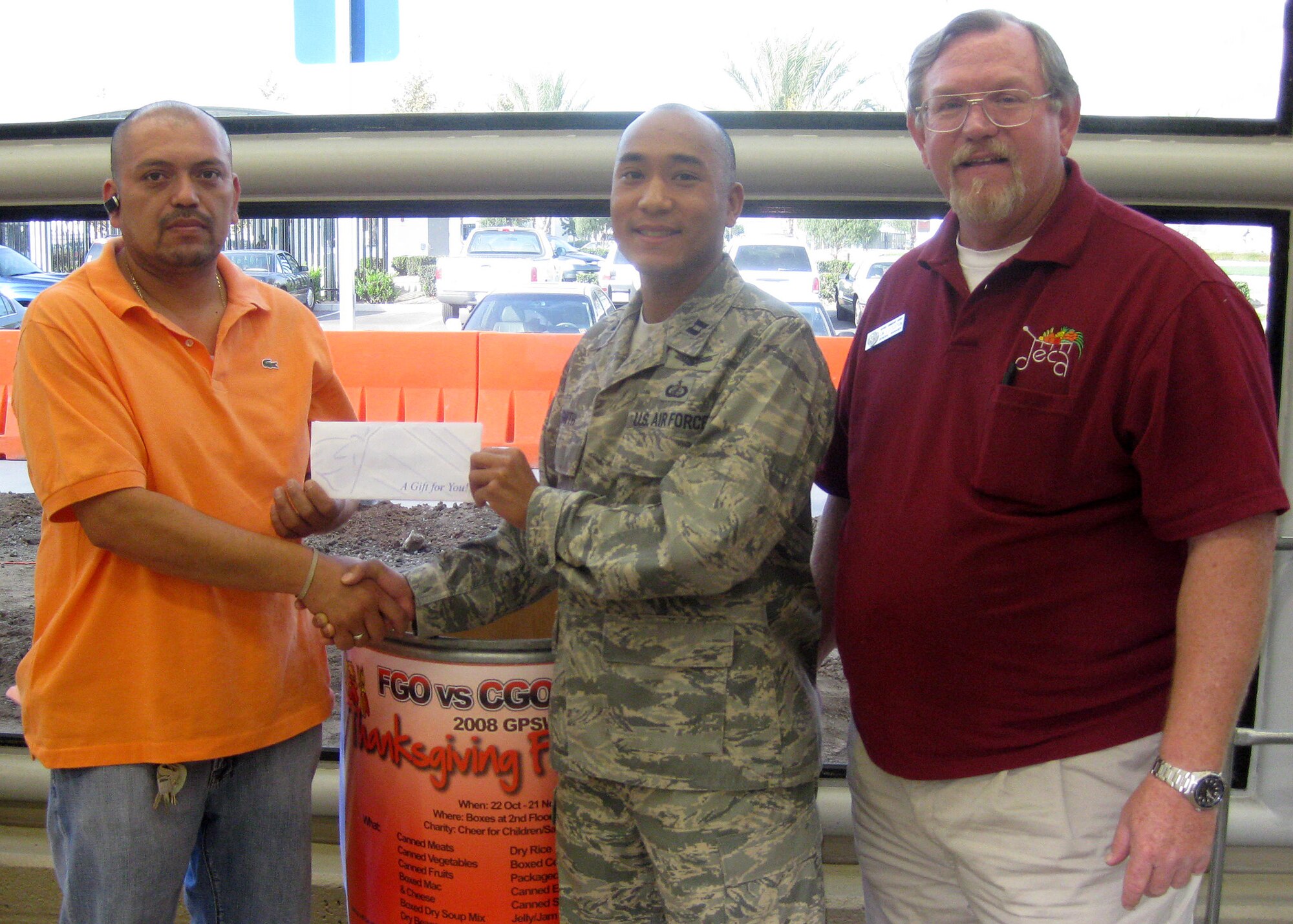 Capt. Trey Smith (center) receives a check for $100 Los Angeles AFB Base Commissary representatives in support of GPSW Thanksgiving Food Drive. (Courtesy photo)