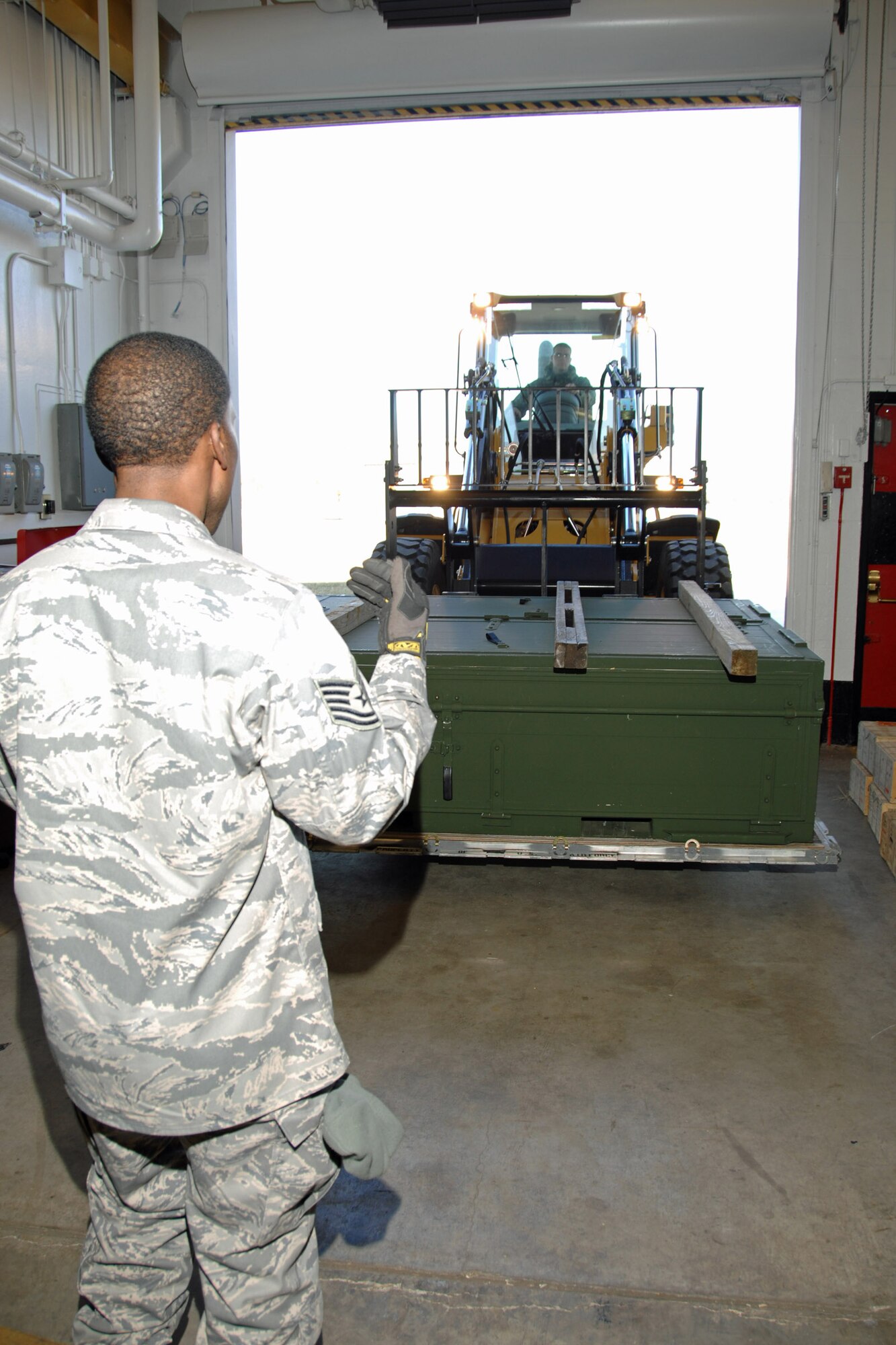 Tech. Sgt. Jason Grant, unit deployment manager for the 88th Security Forces Squadron, guides Staff Sgt. Michael Bigelow, a munitions inspector with the 88th Operations Support Squadron, into a weapons inspection facility at Wright-Patterson Air Force Base. The Airmen removed various ammunition from protective storage and prepared it for containerized shipment during a crisis response deployment exercise Dec. 5. The exercise is part of base preparations for the 2009 Operational Readiness Inspection. (U.S. Air Force photo/Ben Strasser) 