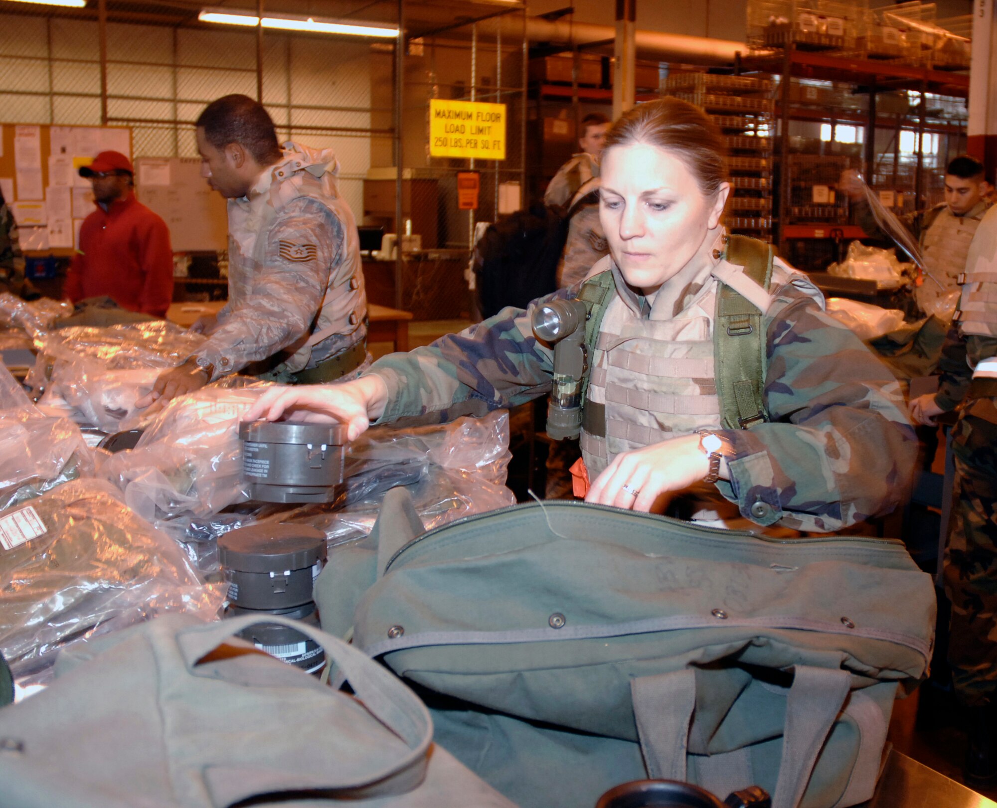 Lt. Col. Cheryl Lewis, 88th Communications Squadron commander, checks out her chemical and biological protective gear inside the Wright-Patterson Air Force Base mobility bag warehouse Dec. 8.  More than 200 base Airmen participated in the exercise which simulated a mass deployment to an air base in Asia.  The exercise is part of base preparations for the 2009 Operational Readiness Inspection  (U.S. Air Force photo/Al Bright) 
