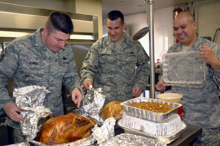 ABILENE, Texas -- Master Sgt. Benjamin Kunde, Senior Master Sgt. Theodore Lambremont, and Master Sgt. John Ruiz unveil a feast of five turkeys, three hams, scalloped creamed corn, sweet potatoes, mashed potatoes, green beans, stuffing, gravy, corn bread, tea and lemonade, and assorted pies during a holiday feast at the Army Reserve Center in Abilene, Texas, Dec. 6. About 20 Dyess Airmen contributed all of the food for the meal in order to bring some holiday cheer to the families of deployed Soldiers in the local area. (U.S. Air Force photo/Senior Airman Carolyn Viss)