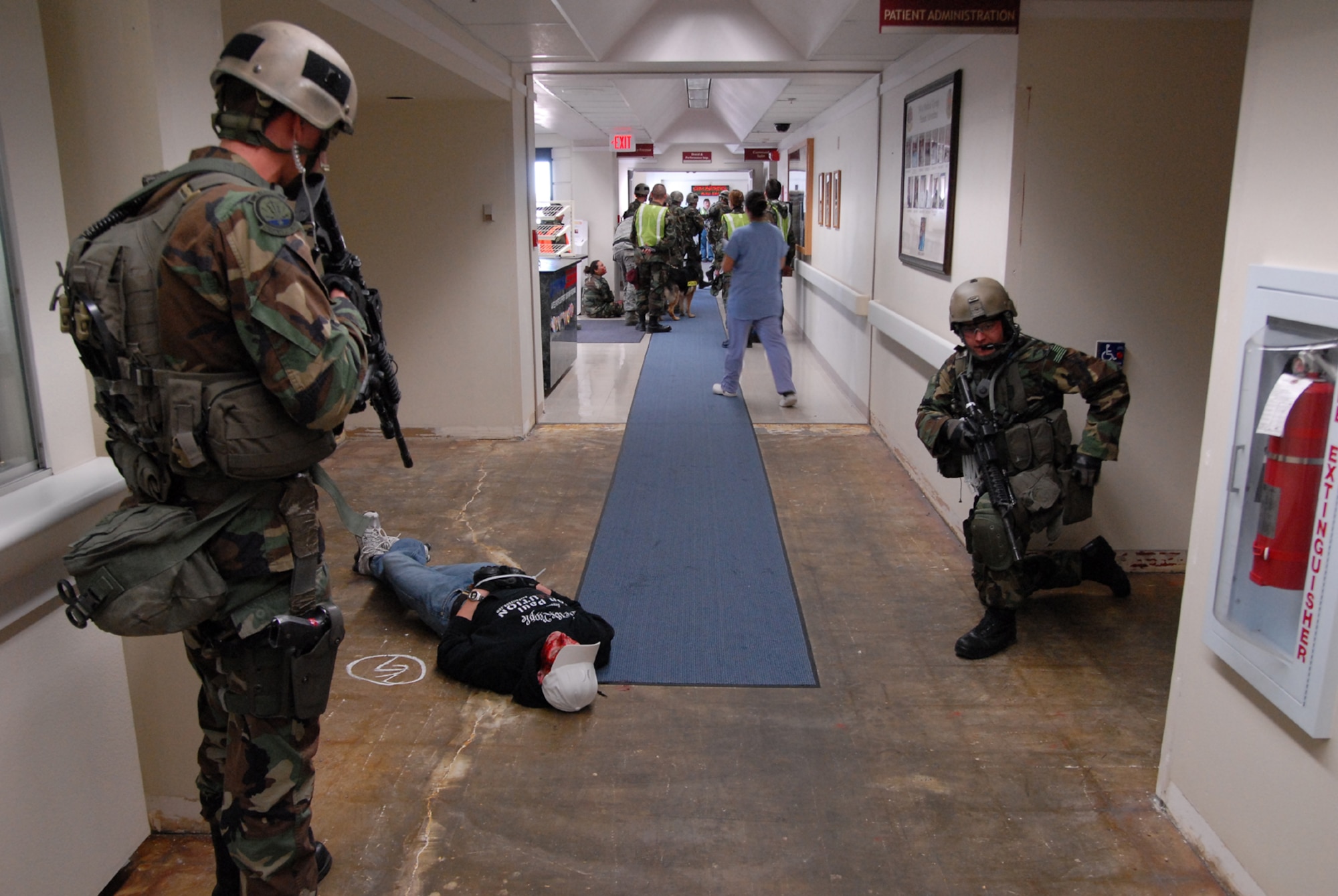 Senior Airman Steve Kooyman (standing) and Staff Sgt. David Barger (kneeling) guard the shooter during an on-base exercise shooting scenario held at the Malmstrom Clinic March 28. The two are members of the 341st Security Forces Group Tactical Response Force. (U.S. Air Force photo/John Turner)