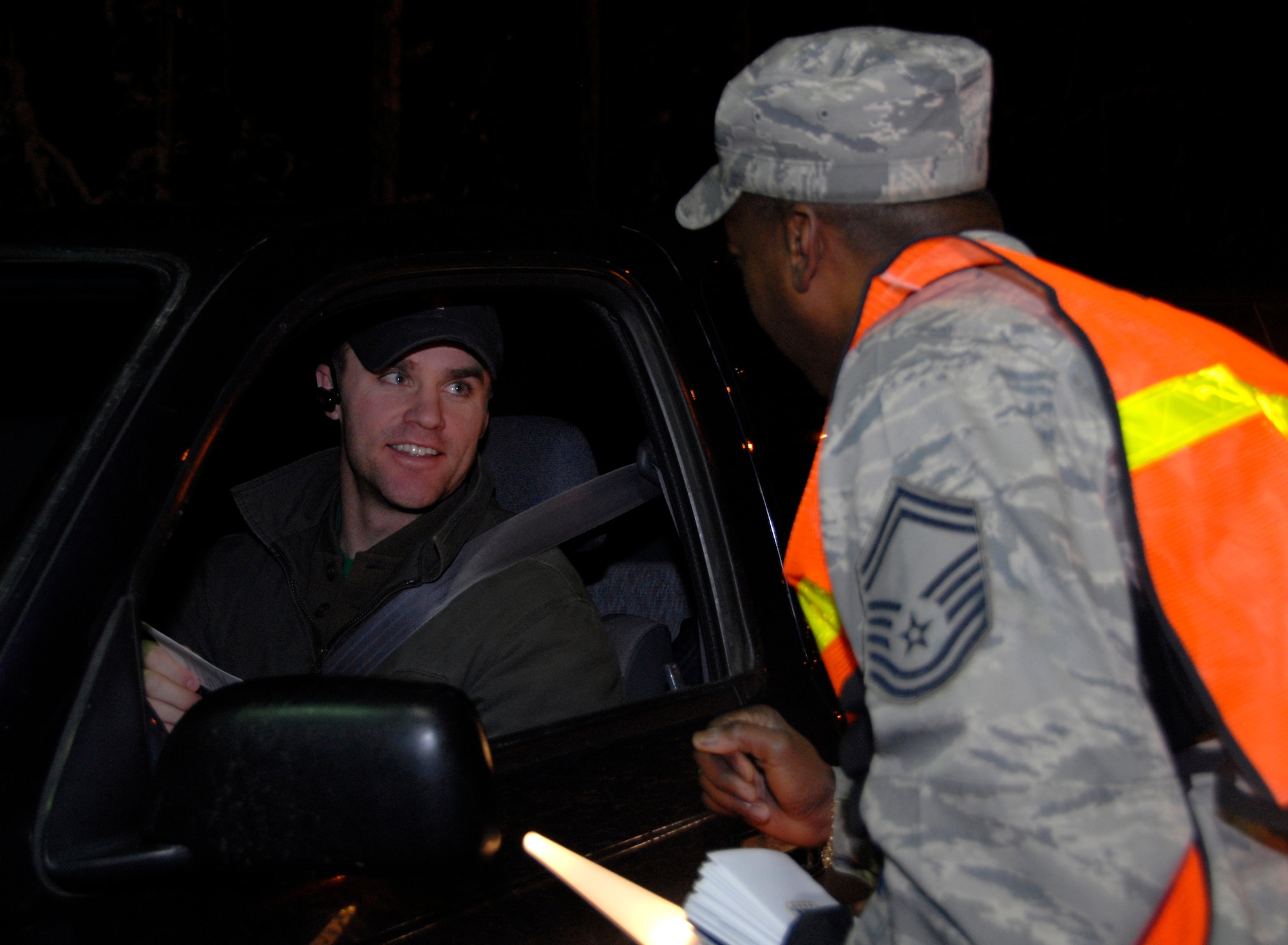 ELMENDORF AIR FORCE BASE, Alaska -- Senior Master Sgt. Dana Belser, 3rd Medical Support Squadron, hands "What's Your Plan?" brochures to vehicles as they leave the base Dec. 6. Sergeant Belser is a volunteer for the Alcohol Task Force which was initiated to help eliminate DUI's on Elmendorf. The Alcohol Task Force will be at the outbound gates from 10 p.m.-midnight Friday and Saturday nights. (U.S. Air Force photo/Airman 1st Class Cynthia Spalding)
