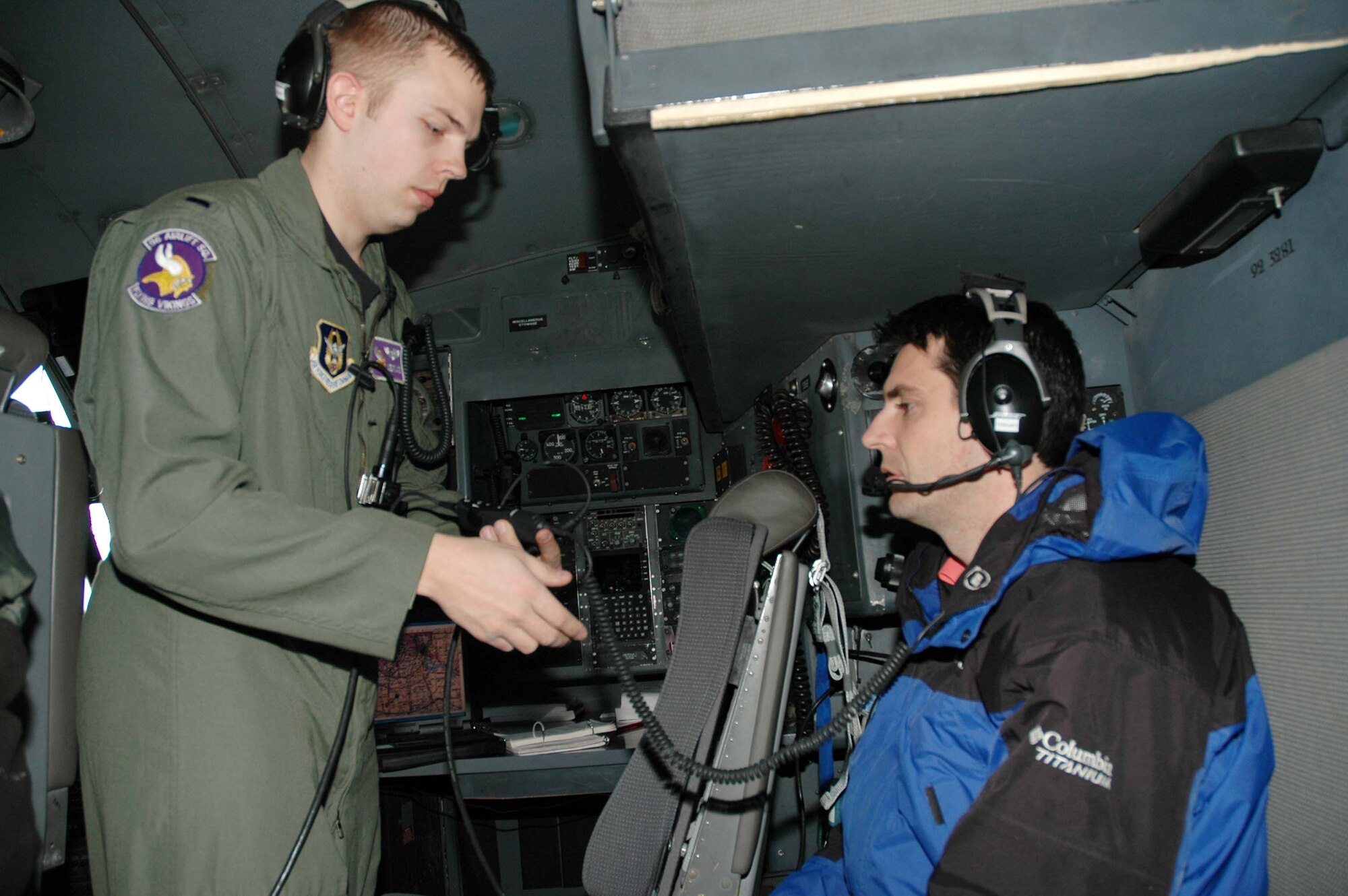 1st Lt. Lee Place, 96th Airlift Squadron navigator, performs a communications check on KARE-TV journalist Jeffrey DeMars' headset during a 934th C-130 media orientation flight Dec. 5. (Air Force Photo/Tech. Sgt. Jeffrey Williams)


