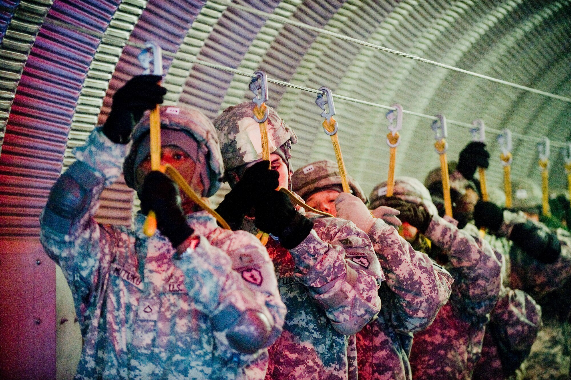 FORT RICHARDSON, Alaska -- Fort Richardson's 725th Brigade Support Battalion jumpers grab a mock static line in preparation for jumping out the mock door at Airborne Sustainment Training Area Dec. 8. The 4th Brigade Combat Team, 25th Infantry Division partnered with the 517th Airlift Squadron is using this week practice jumps prior to the deployment. Roughly 1,300 4-25 Soldiers will be jumping out of C-17 Globemaster IIIs during the week. (U.S. Air Force photo/Senior Airman Jonathan Steffen)