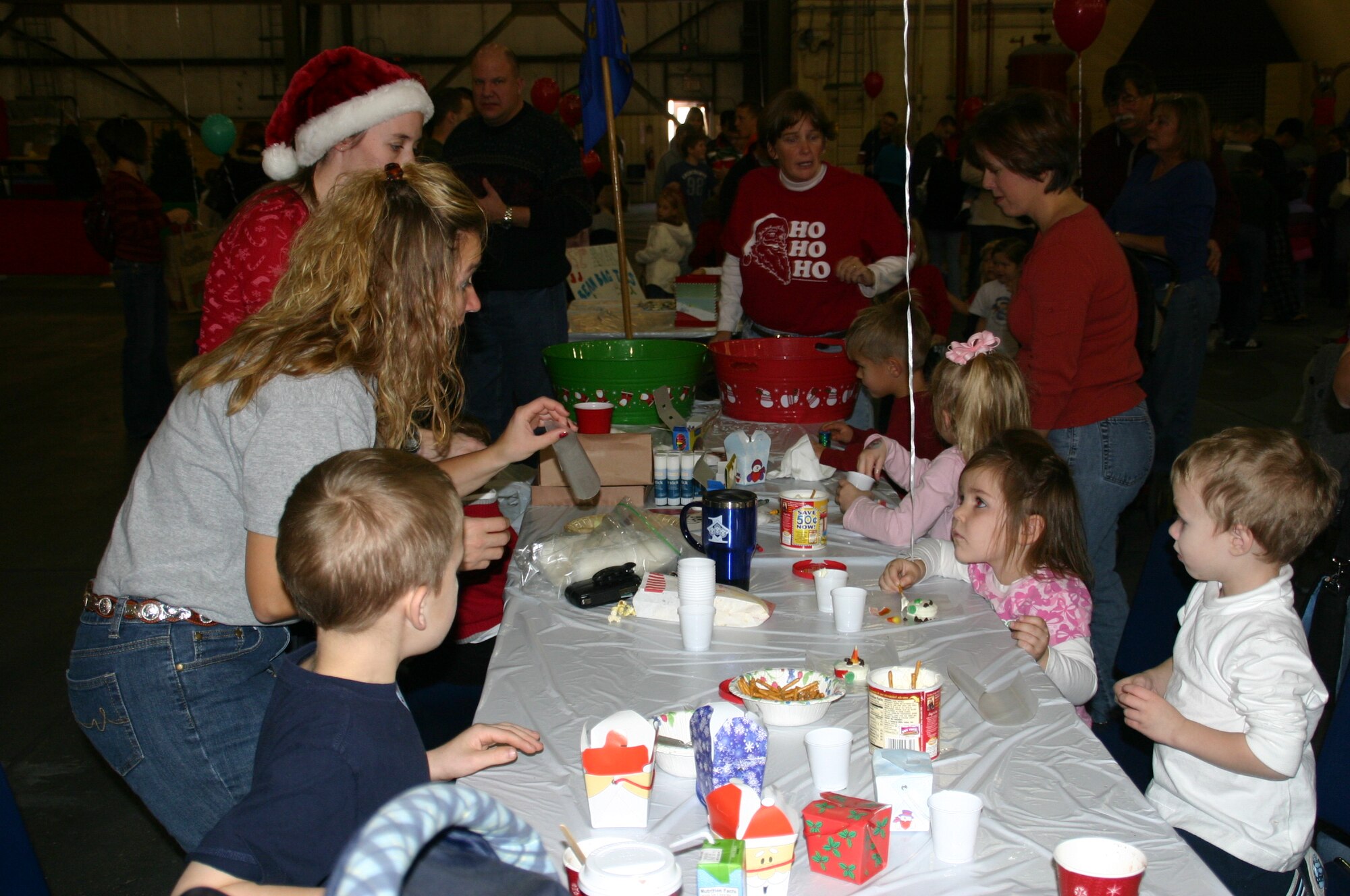 Master Sgt. Glenda Ipock, first sergeant, 964th Airborne Air Control Squadron, helps several children frost cookies and make crafts at the squadron activity tables. Photo courtesy of 1Lt Kinder Blacke.