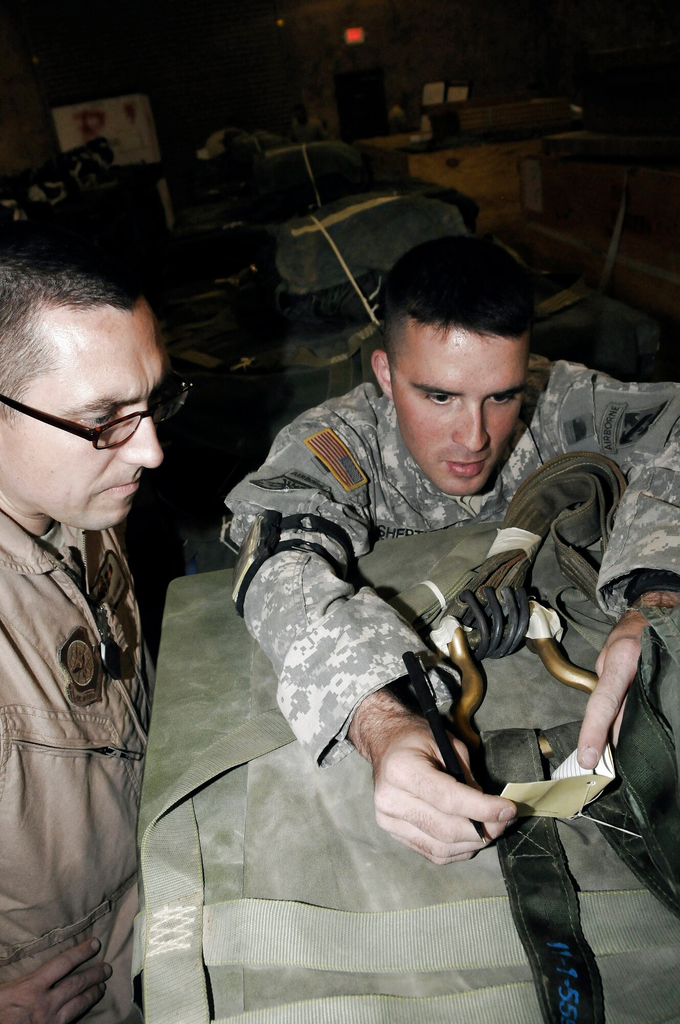 Army Sgt. Joshua Sheptock shows Tech. Sgt. Keith Hackney pertinent information inside of a parachute log book Dec. 6 at an air base in Southwest Asia. This joint inspection was performed to ensure the container delivery system was rigged correctly so it can be used to drop supplies in the area of responsibility. Sergeant Hackney is a C-17 Globemaster III joint airdrop inspector and is assigned to the 816th Expeditionary Airlift Squadron. Sergeant Sheptock is a parachute rigger assigned to the 824th Riggers. (U.S. Air Force photo/Staff Sgt. Darnell T. Cannady)
