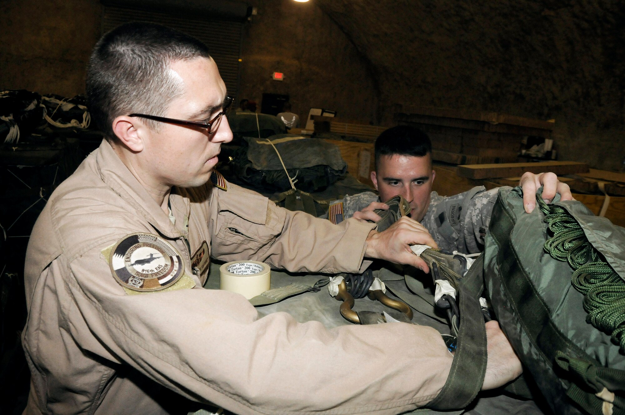Tech. Sgt. Keith Hackney and Army Sgt. Joshua Sheptock perform a joint inspection Dec. 6 at an air base in Southwest Asia to ensure a container delivery system was rigged correctly so it can be used to drop supplies in the area of responsibility. Sergeant Hackney is a C-17 Globemaster III joint airdrop inspector and is assigned to the 816th Expeditionary Airlift Squadron. Sergeant Sheptock is a parachute rigger assigned to the 824th Riggers. (U.S. Air Force photo/Staff Sgt. Darnell T. Cannady)