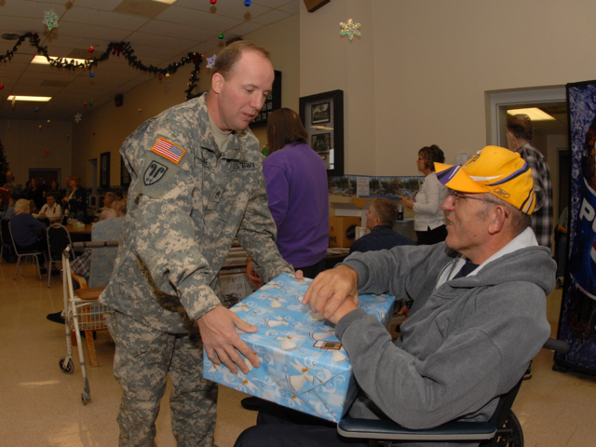 Staff Sgt. Larry Fontaine, N.D. Army National Guard, hands a gift to a Veteran at the North Dakota Veterans Home in Lisbon, N.D. on December, 19, 2007.  
