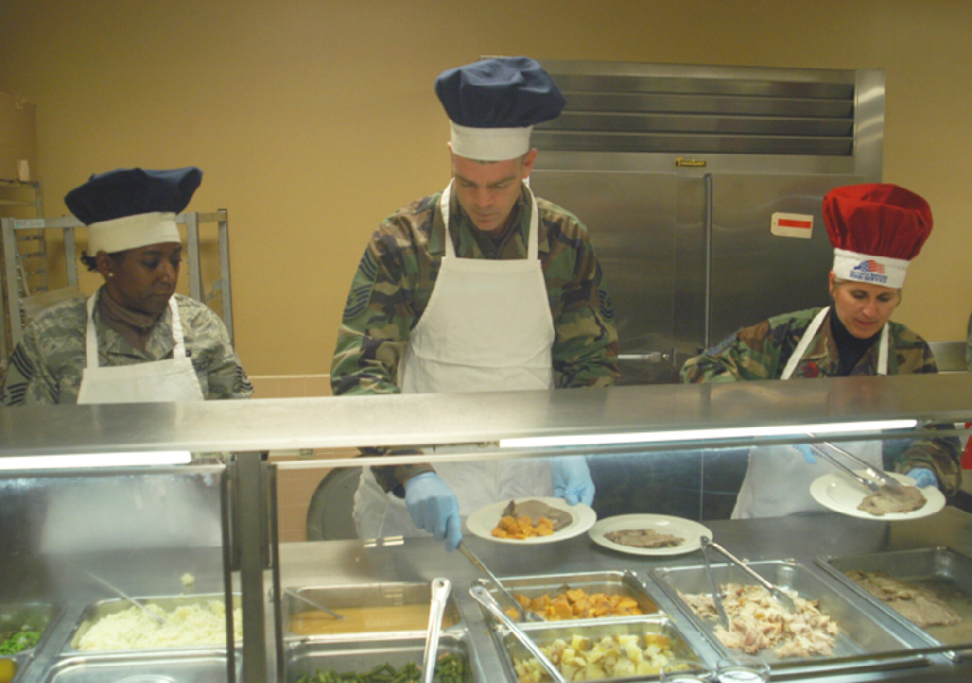 GRISSOM AIR RESERVE BASE, Ind., -- Chief Master Sgt. Peri Rogowski (right), 434th Air Refueling Wing command chief, Chief Master Sgt. Tamara Jones (left), 434th Logistic Readiness Squadron reserve supply superintendent, and Chief Master Sgt. James Owens, 434th Aircraft Maintenance Squadron superintendent, lead by example and put service before self. During the December primary unit training assembly senior leadership assisted the 434th Services Flight during the holiday luncheon by serving food and performing other duties. (U.S. Air Force photo/Senior Airman Carl Berry)