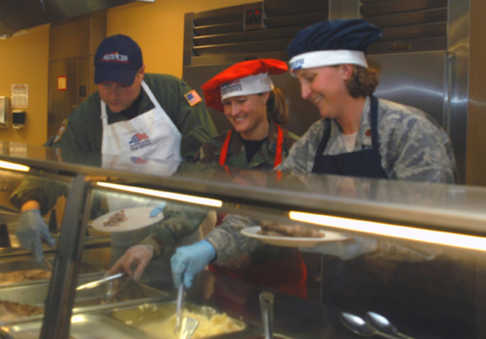 GRISSOM AIR RESERVE BASE, Ind., --  It was all smiles during the holiday luncheon at the Grissom dining facility. Senior leadership helped the 434th Services Flight serve food and perform other duties during the meal. Maj. Rebecca Fox (right), 434th Communication Squadron commander, Capt. Amanda Owens (center), 434th SVF commander, and Lt. Col. Mark Sigler of the 74th Air Refueling Squadron prepare a plate for a hungry unit member. (U.S. Air Force photo/Staff Sgt. Ben Mota)