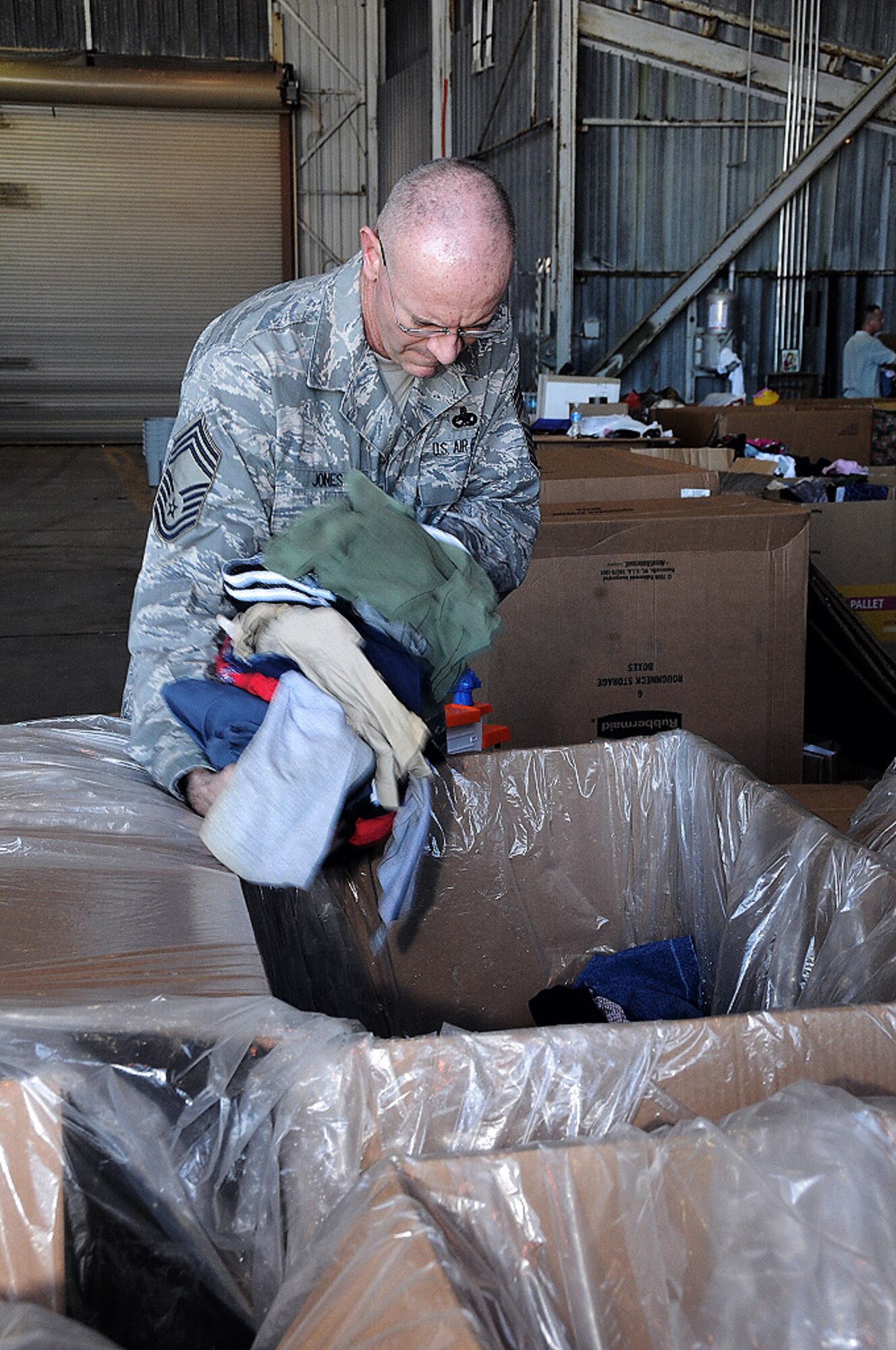 Chief Master Sgt. Steven Jones loads clothes into one of many boxes at Andersen Air Force Base, Guam, Dec. 7. The final box build was held here at Hangar 4 in preparation for airdrops to the Micronesian Islands beginning Dec. 17 through Dec. 21. Chief Jones is the 715th Air Operations Group superintendent at Hickam Air Force Base, Hawaii. (U.S. Air Force photo/Senior Airman Nichelle Griffiths)