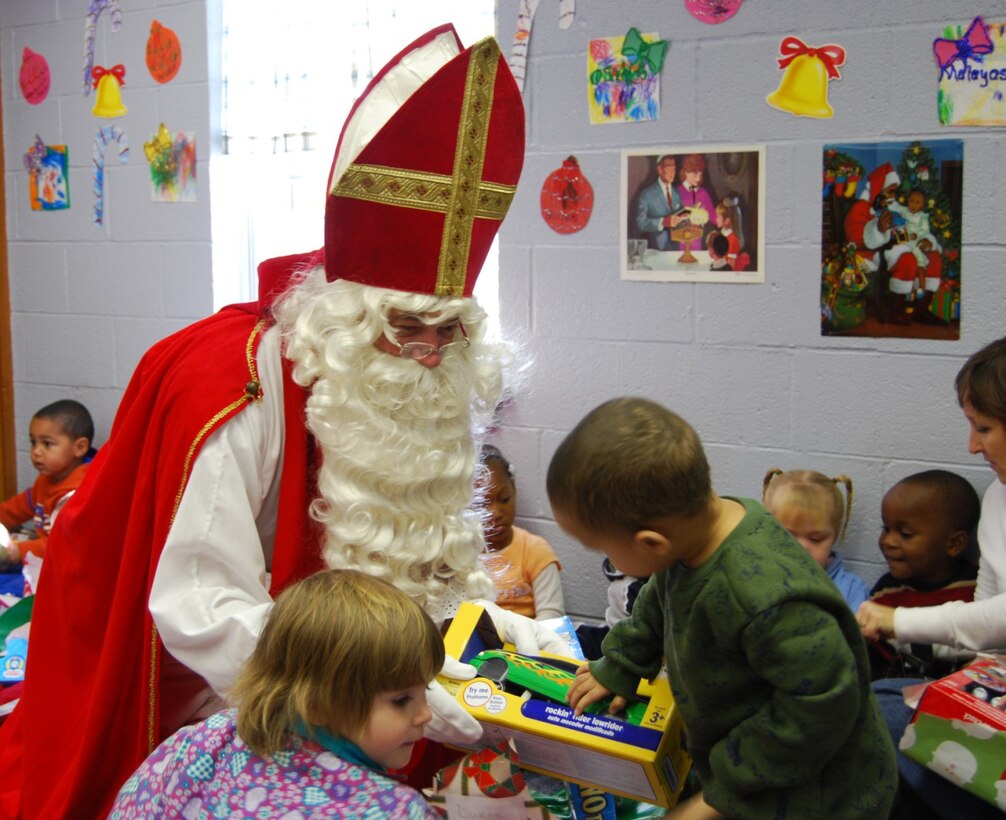 Children from the Ben Donnell Child Care Center  in Wichita Falls, gets his present from Sinterklaas on Dec. 5.  Sinterklaas, the equivalent of Santa Claus, is the gift-giver to the children of The Netherlands.  Members of the Royal Netherlands air force at Sheppard have been giving presents to the lower income children of Ben Donnell for 25 years.  Black Peter, Sinterklaas' assistant, who is covered with soot from sliding down the chimney, helped Sinterklaas hand out the gifts. (U.S. Air Force photo/Mike McKito)