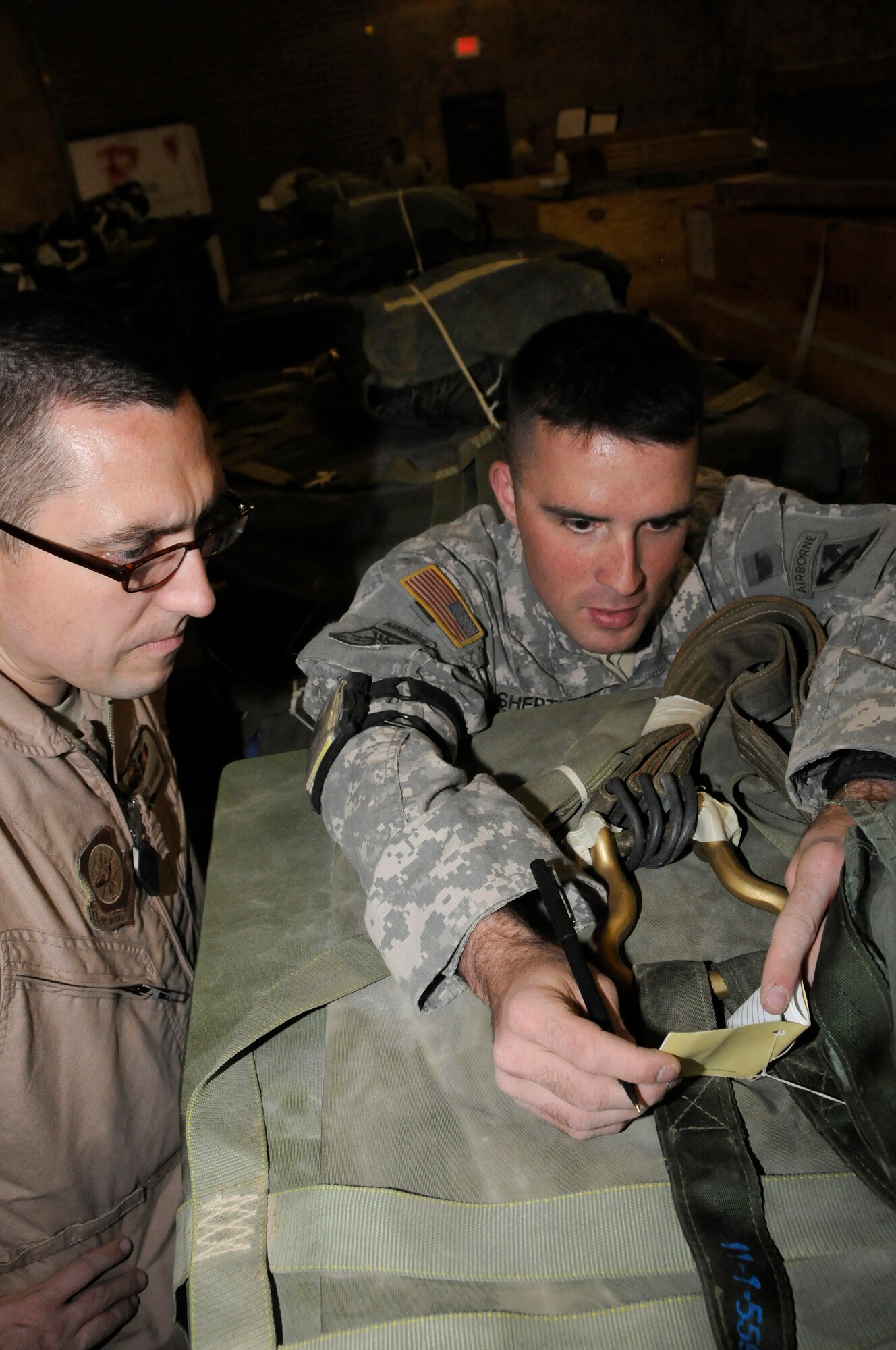 Sgt. Joshua Sheptock, parachute rigger assigned to the 824th Riggers, shows Tech. Sgt. Keith Hackney, C-17 joint airdrop inspector assigned to the 816th Expeditionary Airlift Squadron, pertinent information inside of a parachute log book Dec. 6, 2008, at an undisclosed air base in Southwest Asia. This joint inspection was performed to ensure the container delivery system was rigged correctly so it can be used to drop supplies in the area of responsibility. Sergeant Hackney, a native of Frederick, Md., is deployed from Charleston Air Force Base, S.C., and Sergeant Sheptock, a native of Fayetteville, N.C., is deployed from Fort Bragg, N.C. Both are deployed in support of Operations Iraqi and Enduring Freedom and Joint Task Force-Horn of Africa. (U.S. Air Force photo by Staff Sgt. Darnell T. Cannady/Released)