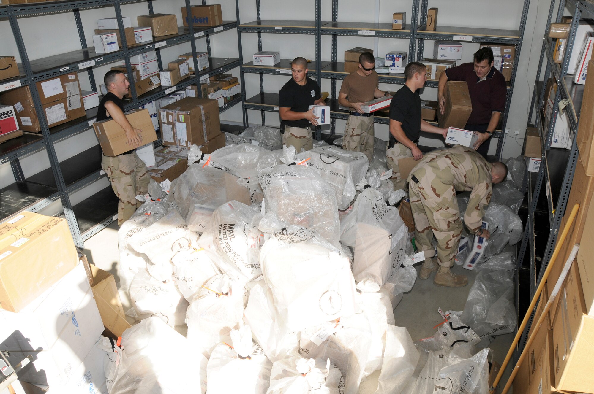SOUTHWEST ASIA -- Members of the 380th Expeditionary Civil Engineer Fire and Emergency Services help sort through incoming mail here Dec. 8. The Fire Department works alongside Alutiiq International Solutions LCC. This company is contracted to provide personnel and services for the 380th Air Expeditionary Wing Post Office. They are busy trying to keep the mail coming and going during the busy holiday season. (U.S. Air Force photo/Tech. Sgt. Christopher A. Campbell)(released)
