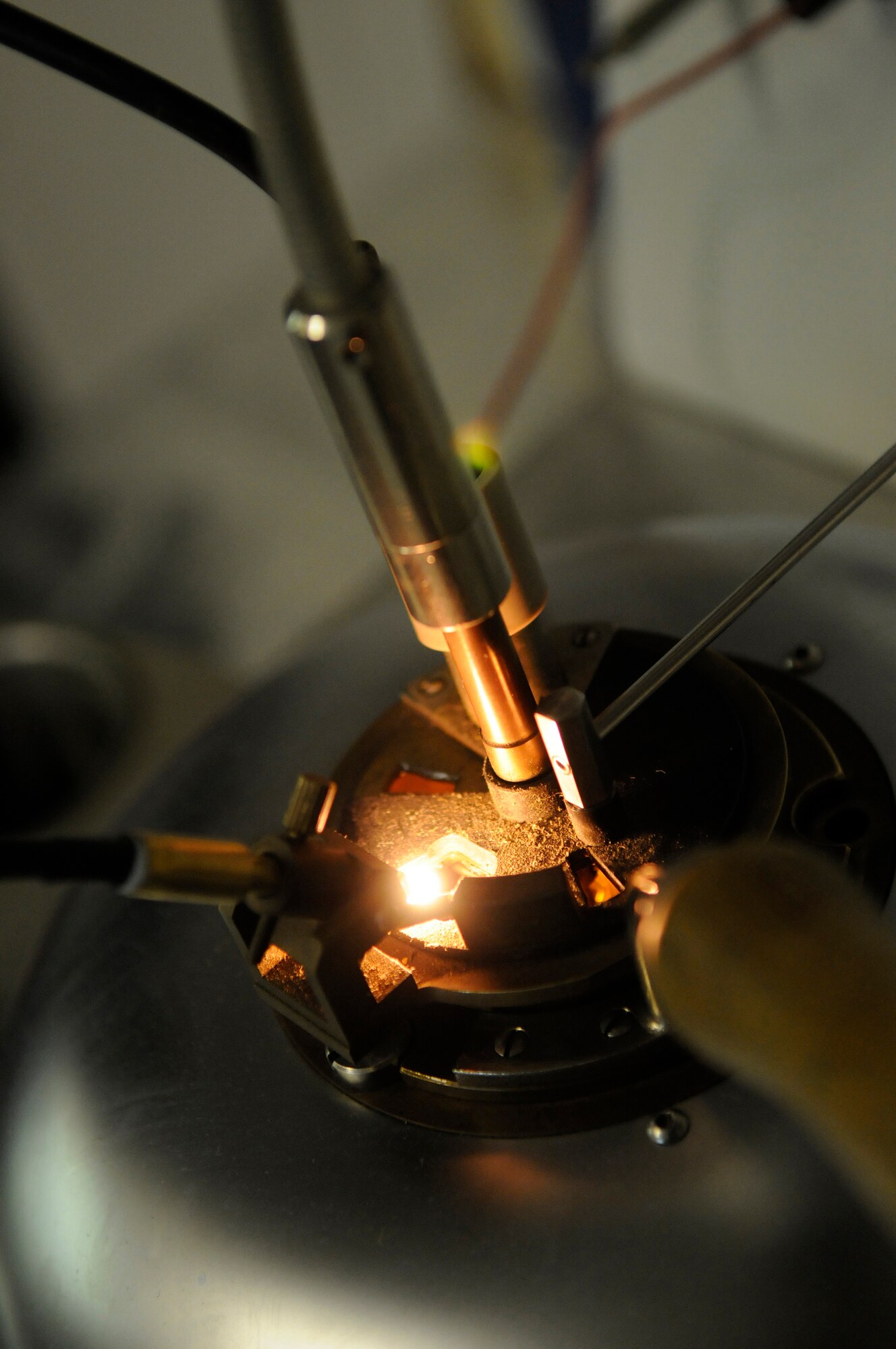 An ignition coil is exposed over JP-8 fumes during a flash point test Dec. 8, at an undisclosed air base in Southwest Asia.  Staff Sgt. Ronald Gasper, a fuels lab technician assigned to the 379th Expeditionary Logistics Readiness Squadron, uses a flash tester to perform a flash point test. The flash point test is used to determine the temperature at which the fuel will ignite.  The fuel is slowly warmed and every two degrees an ignition coil is briefly exposed over the fuel to identify how hot the fumes must be to ignite.  Sergeant Gasper, a native of Omaha, Neb., is deployed from Scott Air Force Base, Ill., in support of Operations Iraqi and Enduring Freedom and Joint Task Force-Horn of Africa.  (U.S. Air Force photo by Tech. Sgt. Michael Boquette/Released)
