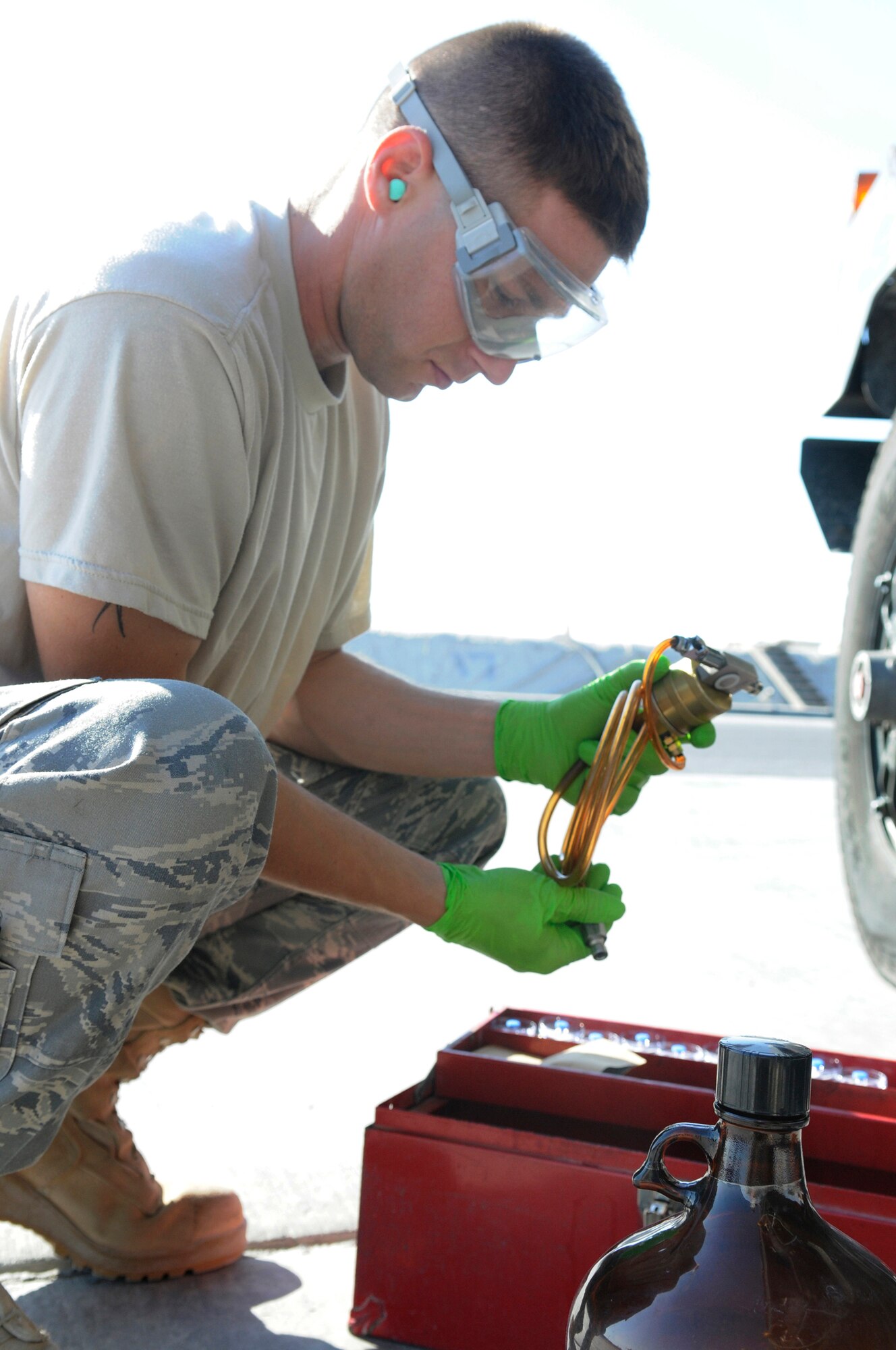 Staff Sgt. Ronald Gasper, a fuels lab technician assigned to the 379th Expeditionary Logistics Readiness Squadron, examines a hose and stopper used for filling a bottle with JP-8 fuel so he can perform a bottle method test of the fuel, Dec. 8, at an undisclosed air base in Southwest Asia. The bottle method test is used to test a fuel truck's filter separator and measures the amount of impurities in the fuel.  Sergeant Gasper, a native of Omaha, Neb., is deployed from Scott Air Force Base, Ill., in support of Operations Iraqi and Enduring Freedom and Joint Task Force-Horn of Africa.  (U.S. Air Force photo by Tech. Sgt. Michael Boquette/Released)