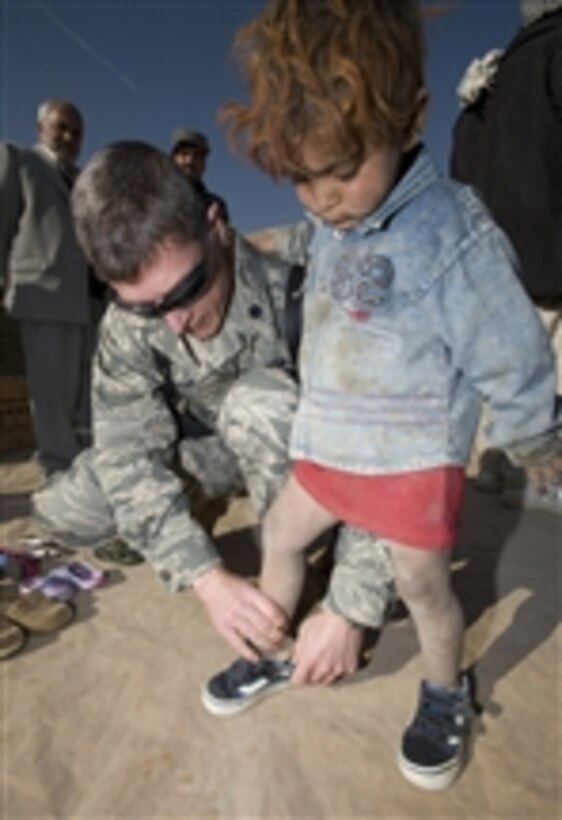 U.S. Air Force Lt. Col. Thomas Knolmayer helps an Afghan girl try on donated shoes at a humanitarian assistance visit to the Parwan Refugee Camp in Afghanistan on Dec. 3, 2008.  U.S. citizens donated clothes, shoes, coats and blankets to the refugee camp through Operation Care.  