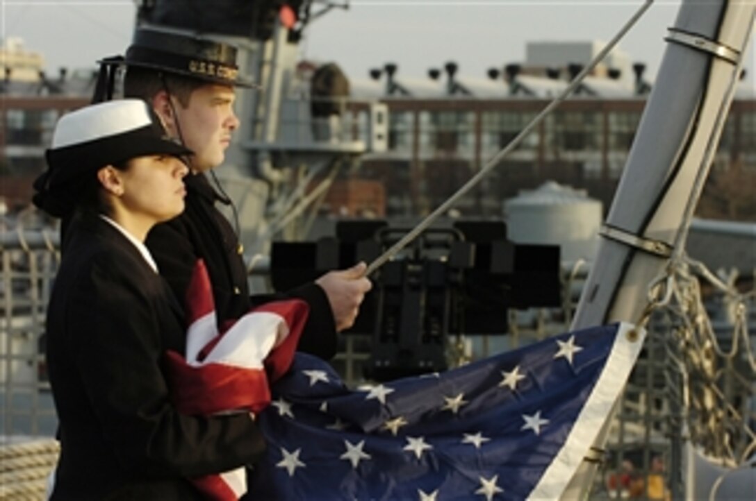 U.S. Navy Chief Quartermaster Stephanie Kotatis (left) and Boatswainís Mate Seaman Dustin Foster, a sailor assigned to the USS Constitution, stand by to commence raising the colors aboard the littoral combat ship USS Freedom (LCS 1) at Boston, Mass., on Dec. 6, 2008.  The Freedom is the first of two littoral combat ships designed to operate in shallow water environments to counter threats in coastal regions.  