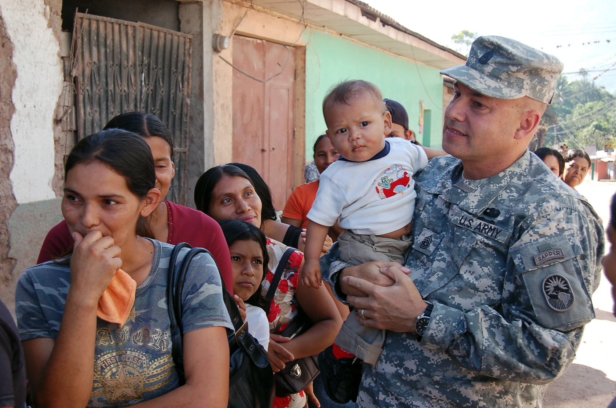 Army Command Sgt. Maj. Michael Balch socializes with people in line for gift baskets containing food, Dec. 9, at Ajuterique, Honduras. The town contains 11,000 people affected by recent flooding. Sergeant Balch is assigned to U.S. Southern Command. (U.S. Air Force photo) 
