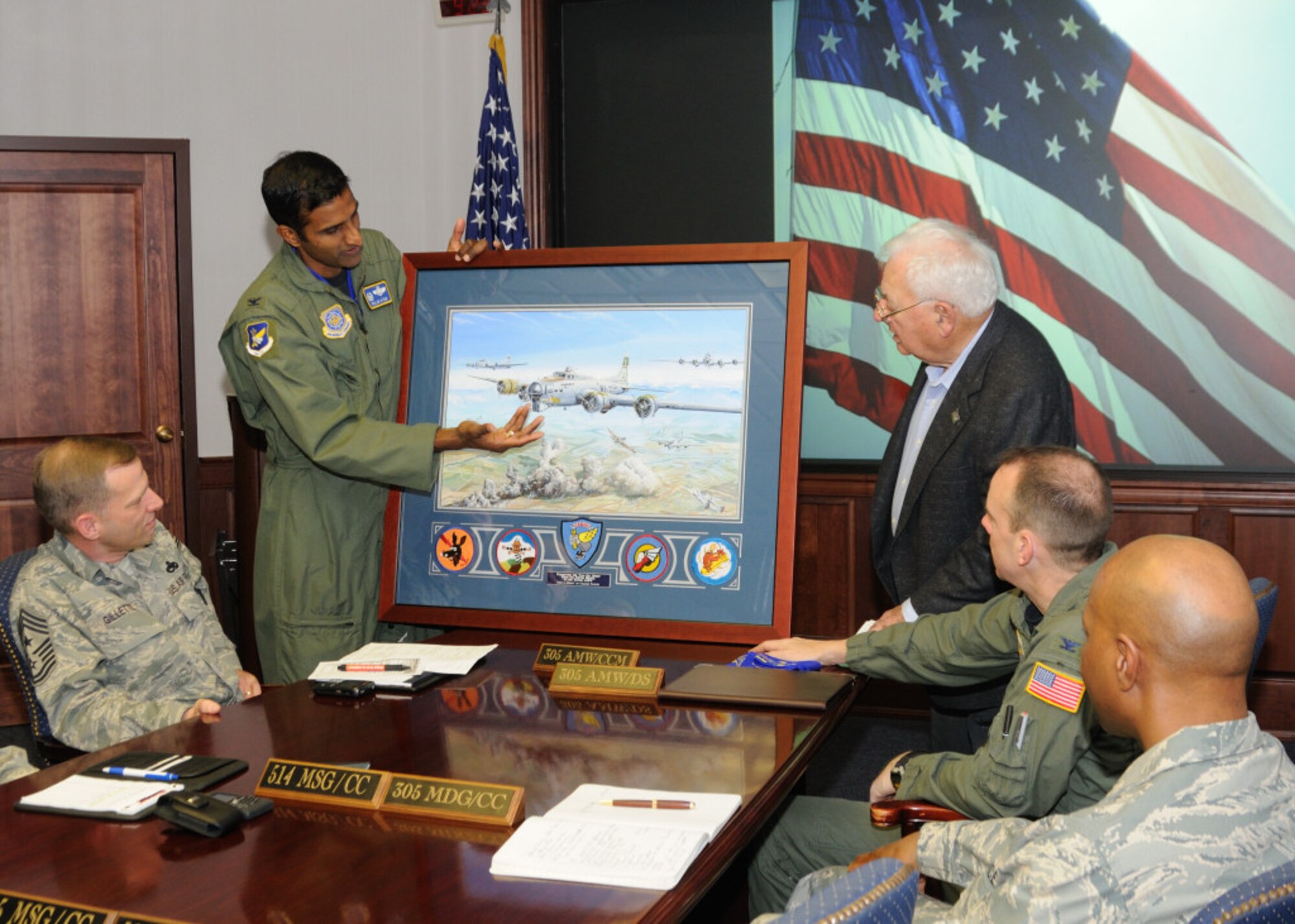 Right, Dave Nagel, former 305th Bomb Group member and former 305th Air Mobility Wing honorary commander, presents Col. Balan Ayyar, 305th AMW commander, and Team McGuire a customized artwork of World War II during a wing meeting Dec. 10. Mr. Nagel has been an active member of the 305th BG Association since it was founded.  He has been the WWII veteran’s link to McGuire since the unit moved here, and has been meeting with commanders and being a goodwill ambassador for the 305th BG Association since 1995. (Photo courtesy of Kimberly Peterson)