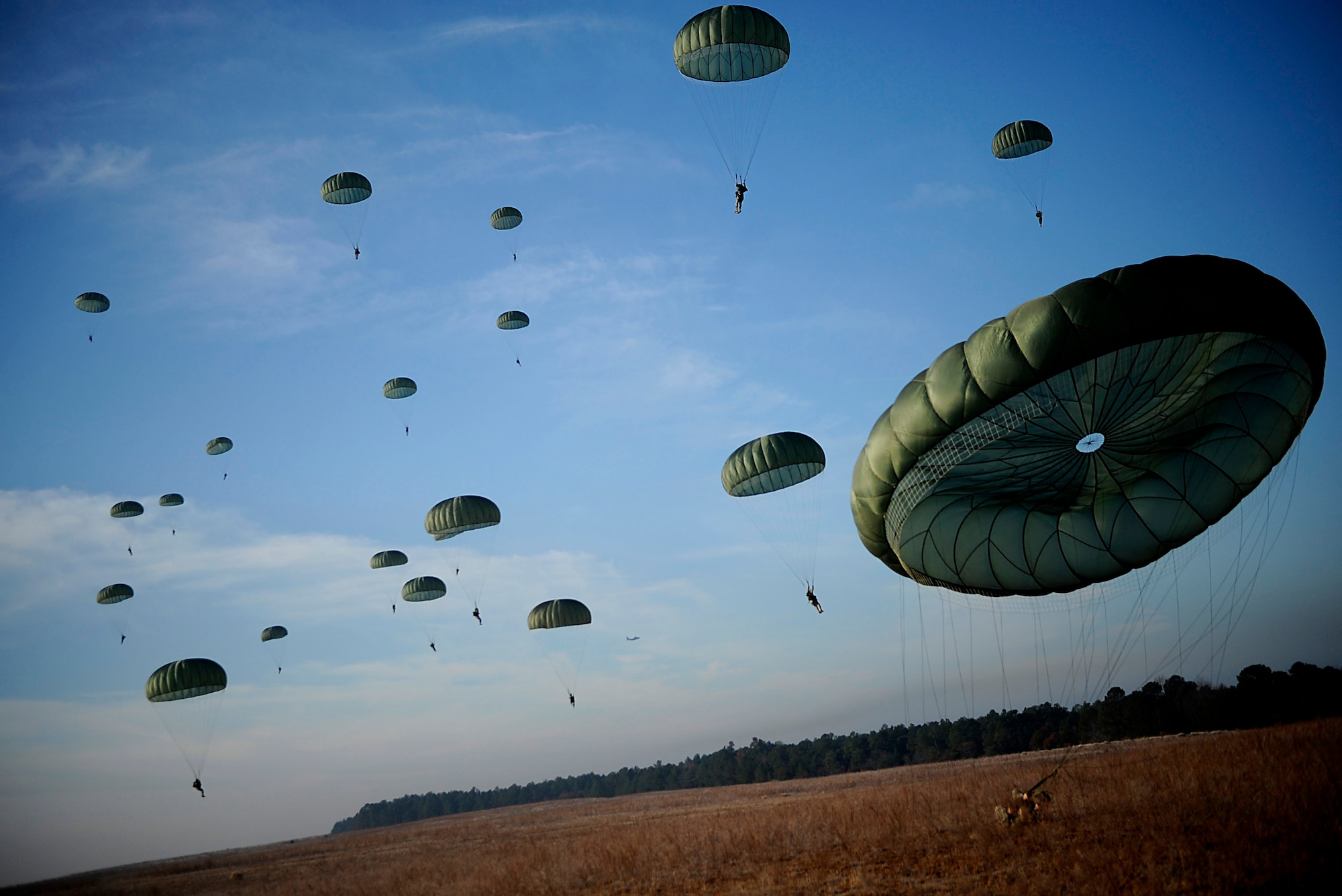 Army Soldiers from the 82nd Airborne Division from Fort Bragg, N.C., descend under parachute canopies to earn foreign jump wings Dec. 6 during Operation Toy Drop at Fort Bragg, N.C. Operation Toy Drop is an annual Airborne jump at Fort Bragg in its 11th year hosted by the Army Civil Affairs and Psychological Operations Command (Airborne), and supported by Fort Bragg's XVIII Airborne Corps and the Air Force Reserve Command's 440th Airlift Wing at Pope Air Force Base that gives Soldiers and Airmen the opportunity to help local families in need over the holidays while boosting morale and incorporating valuable training. More than 3,000 Soldiers donated a toy for a lottery ticket and the chance to jump under a foreign jumpmaster, earning them their foreign jump wings. This year, German and Irish jumpmasters will be issuing the commands from C-130 Hercules aircraft during the operation. (U.S. Air Force photo/Tech. Sgt. Jeremy Lock) 
