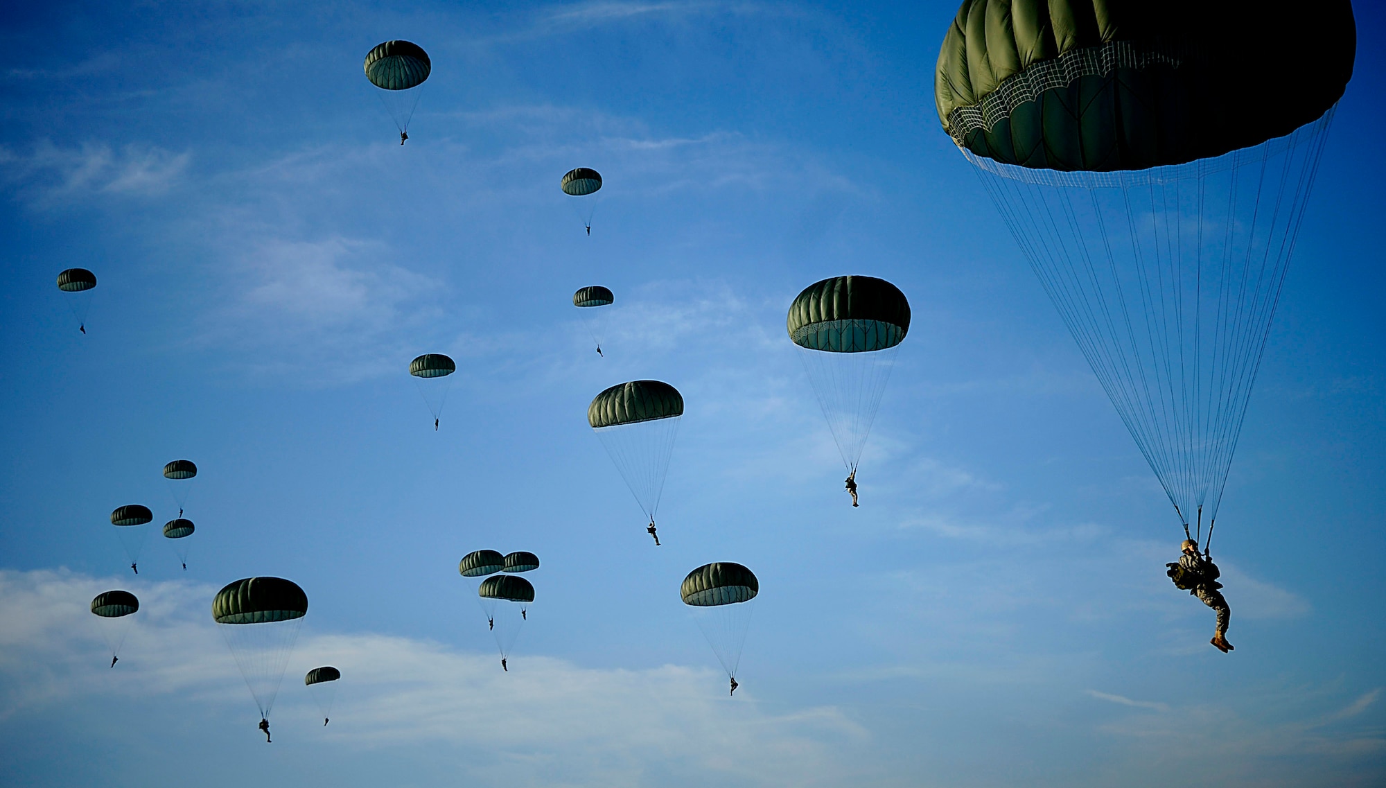 Army Soldiers from the 82nd Airborne Division from Fort Bragg, N.C., descend under parachute canopies to earn foreign jump wings Dec. 6 during Operation Toy Drop at Fort Bragg, N.C. Operation Toy Drop is an annual Airborne jump at Fort Bragg in its 11th year hosted by the Army Civil Affairs and Psychological Operations Command (Airborne), and supported by Fort Bragg's XVIII Airborne Corps and the Air Force Reserve Comman's 440th Airlift Wing at Pope Air Force Base that gives Soldiers and Airmen the opportunity to help local families in need over the holidays while boosting morale and incorporating valuable training. More than 3,000 Soldiers donated a toy for a lottery ticket and the chance to jump under a foreign jumpmaster, earning them their foreign jump wings. This year, German and Irish jumpmasters will be issuing the commands from C-130 Hercules aircraft during the operation. (U.S. Air Force photo/Tech. Sgt. Jeremy Lock) 

