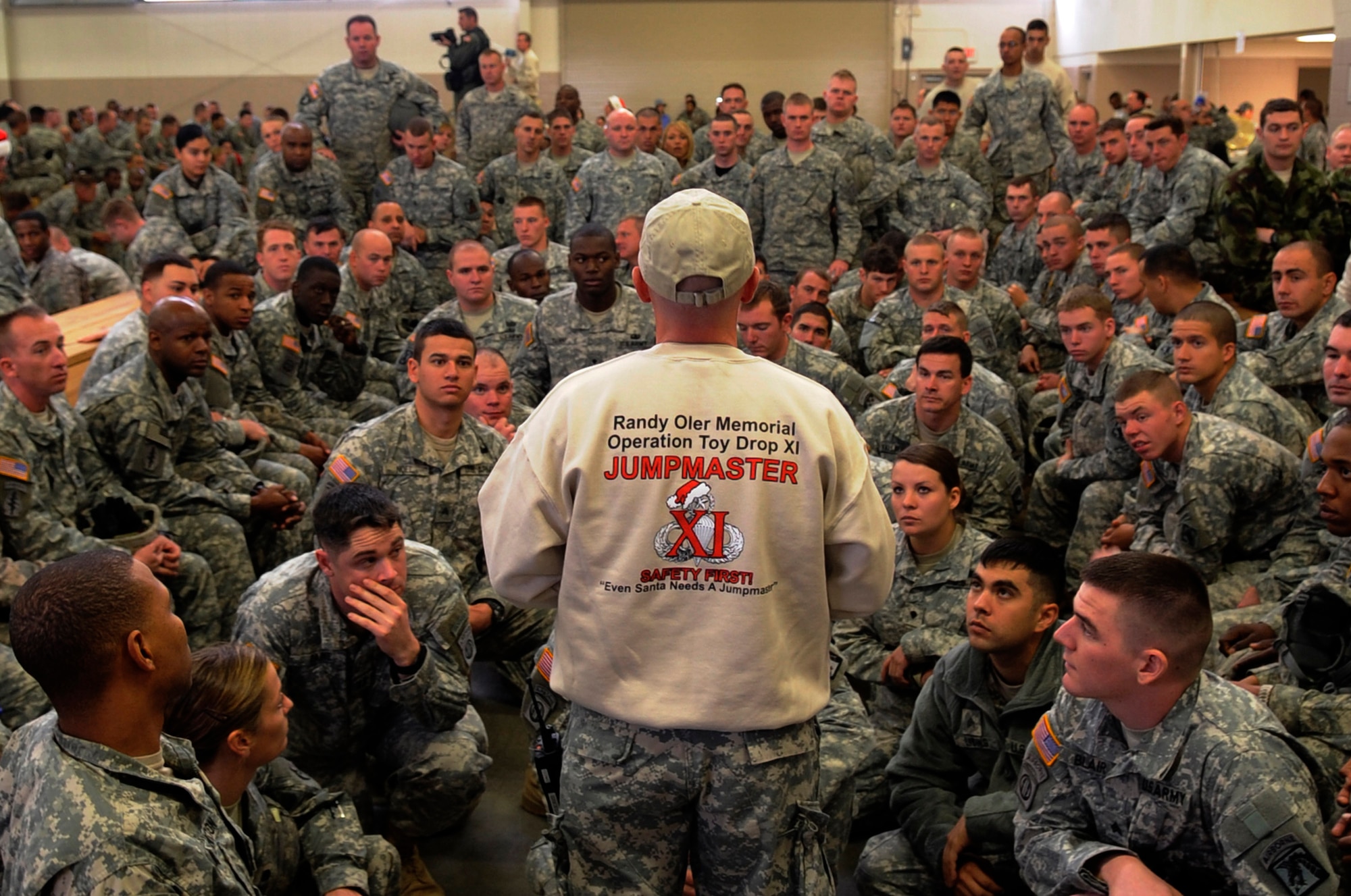 Army Sgt. 1st Class Jason McLoud of the 82nd Airborne Division from Fort Bragg, N.C., gives a jump brief to a group of Soldiers selected to earn foreign jump wings Dec. 5 during Operation Toy Drop at Pope Air Force Base, NC. Operation Toy Drop is an annual Airborne jump at Fort Bragg in its 11th year hosted by the Army Civil Affairs and Psychological Operations Command (Airborne), and supported by Fort Bragg's XVIII Airborne Corps and the Air Force Reserve Command's 440th Airlift Wing at Pope AFB that gives Soldiers and Airmen the opportunity to help local families in need over the holidays while boosting morale and incorporating valuable training. More than 3,000 Soldiers donated a toy for a lottery ticket and the chance to jump under a foreign, jumpmaster earning them their foreign jump wings. This year, German and Irish jumpmasters will be issuing the commands from C-130 Hercules aircraft during the operation. (U.S. Air Force photo/Tech. Sgt. Jeremy Lock) 
